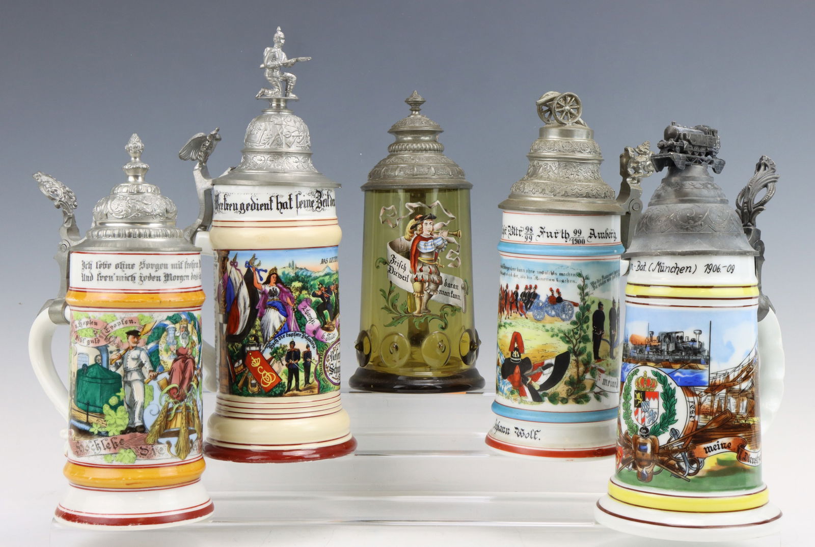 Stein Collection-Including 2-Regimental Steins: Collection of 4 late 19th/Early 20th century steins including; 1.) Glass stein with enamel fired decoration and pewter lid. Stein with lid measures 9" in height. 2.) Porcelain stein for Brewmeister wi