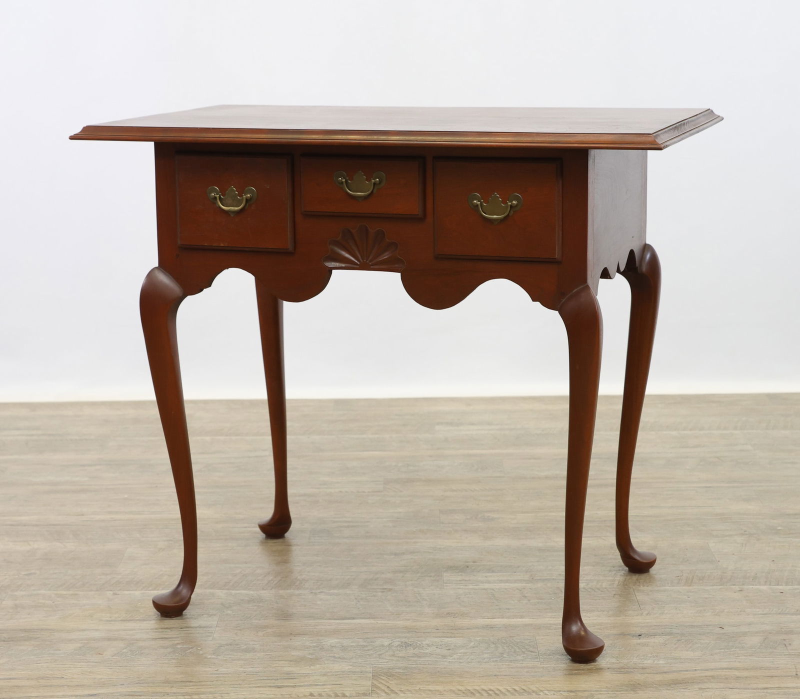 Eldred Wheeler Hand-Crafted Dressing Table: Cherrywood with dovetail and peg consrtuction having a chamfered top over three drawers, shaped apron with a center carved foliate motif on cabriole legs and pad feet. Made in Massachusettes. 31"h x