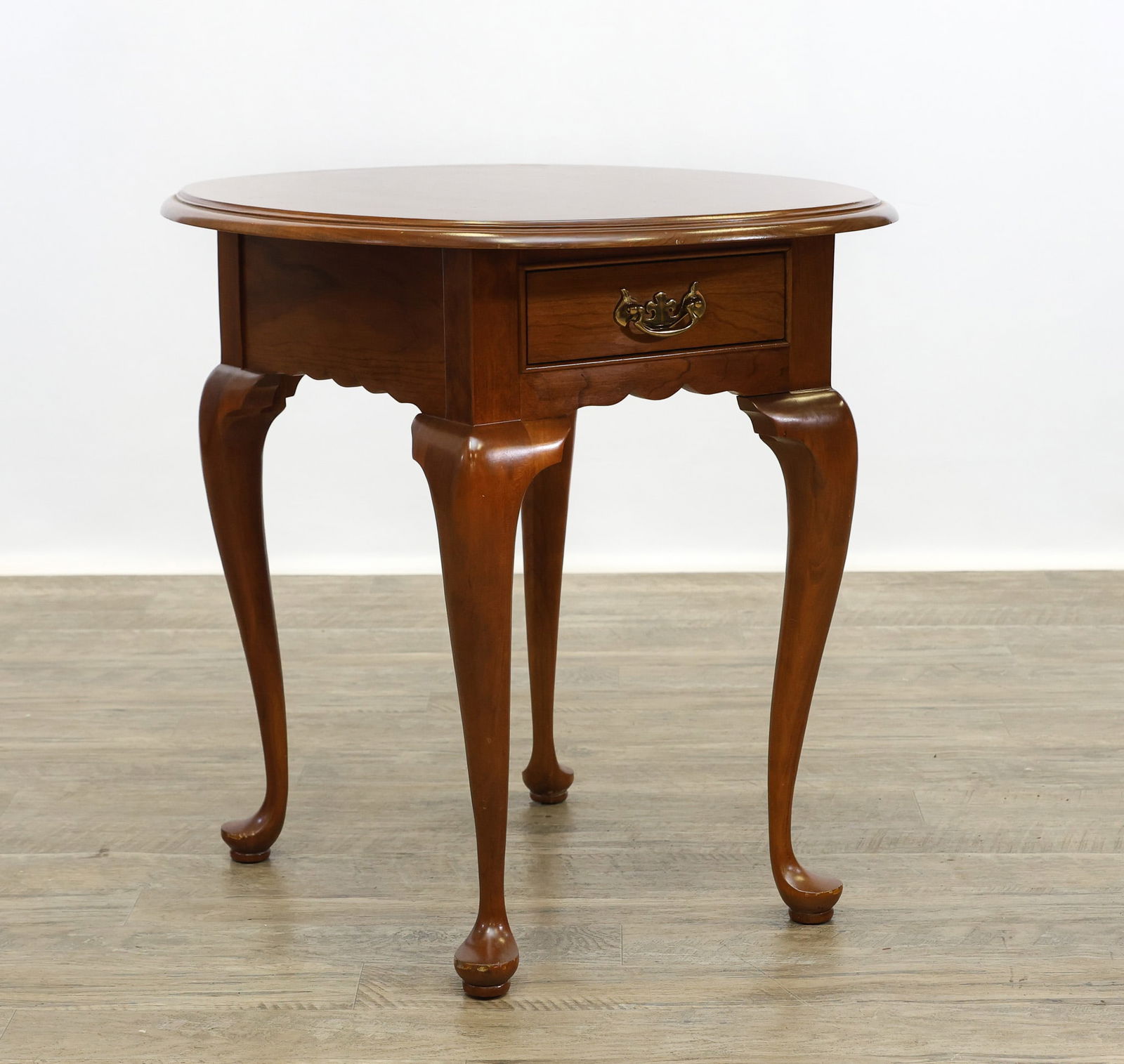 L. & J.G. Stickley Queen Anne Oval Lamp Table: In the Queen Anne style. Wild cherry having a chamfered oval top, one drawer, shaped apron on cabriole legs and pad feet. No. 4503. 25.5"h x 23"w x 27"d