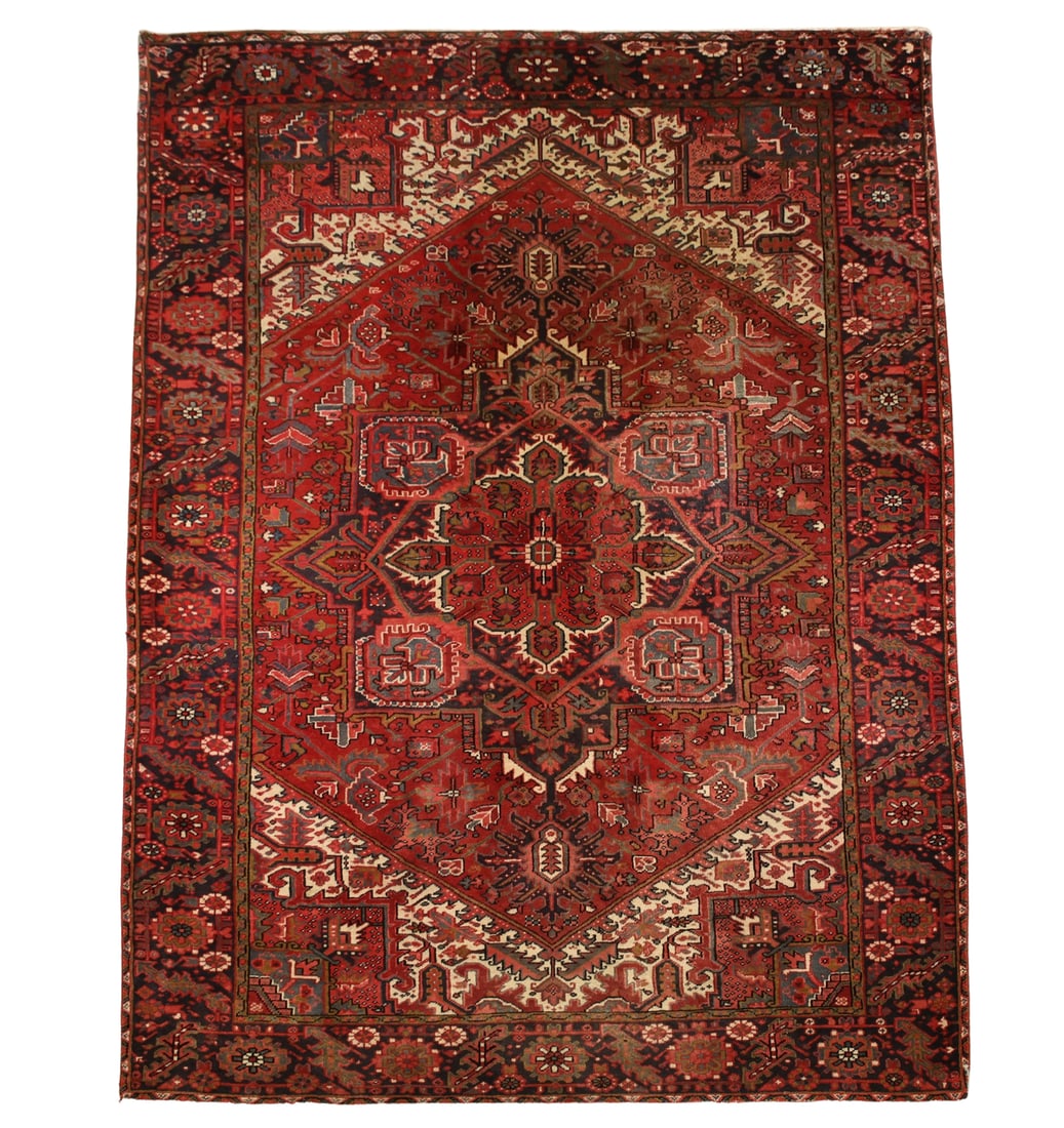 Persian Heriz Rug: Hand knotted with a geometric four corner and lobed central medalllion with pendants, foliate pattern in the field with an alternating flowerhead and foliate main border. Polycrhome colors of red,