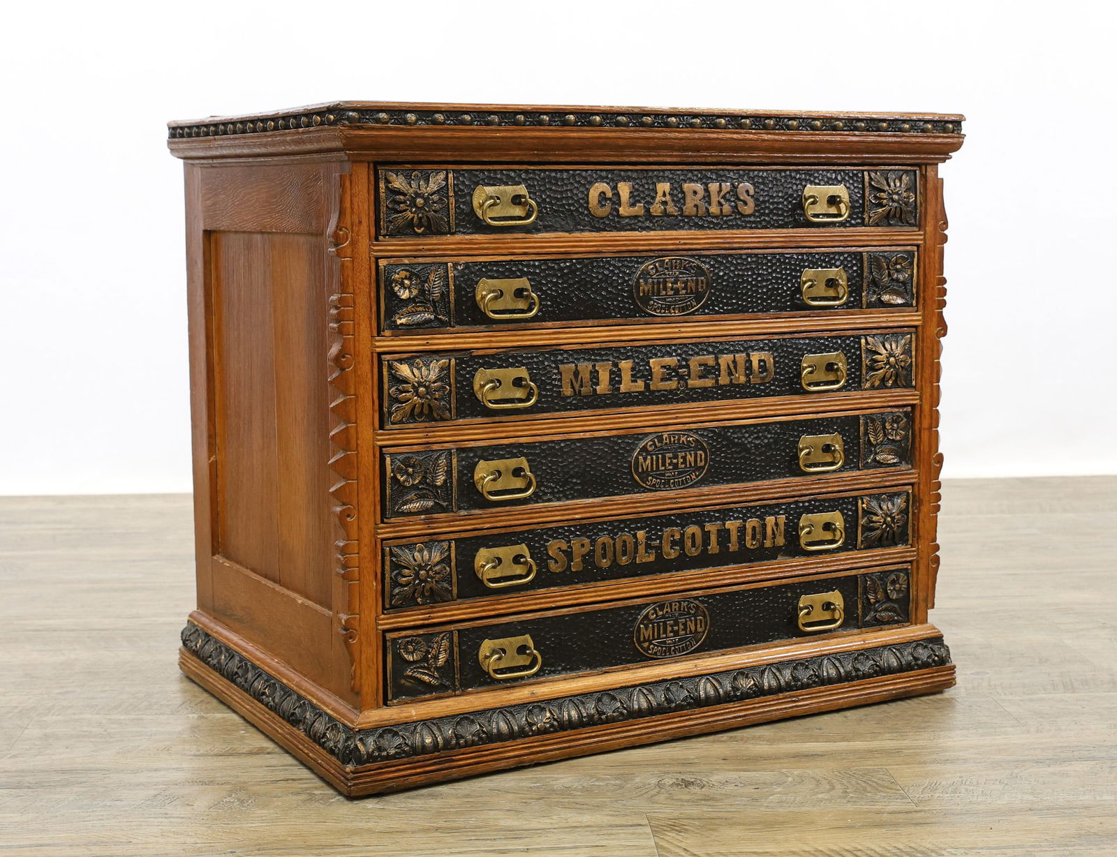 Clark's Mile-End Spool Cabinet: Oak case with pine secondary, sphere molded cornice, six chipped carved gilt and black painted drawers with foliate decoration with brass hardware on carved decorated plinth base. Top of the cabinet s