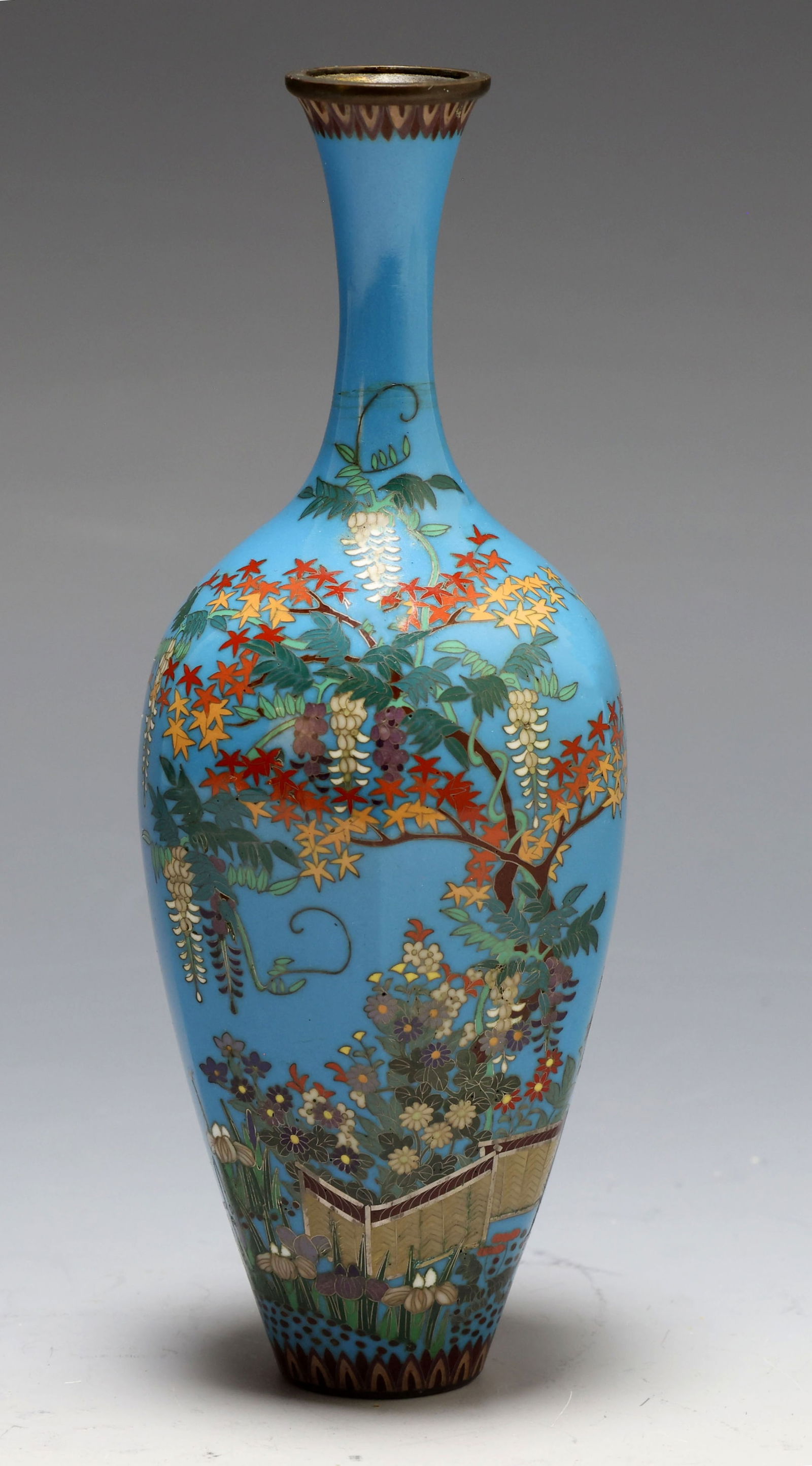 Japanese Cloisonne Vase: Meiji - Taisho era silver wire cloisonne hexagonal vase decorated with wisteria, maple, and other flowers in a garden, with plantain leaf borders, on a sky blue ground. Unmarked. 6"h x 2.25"w