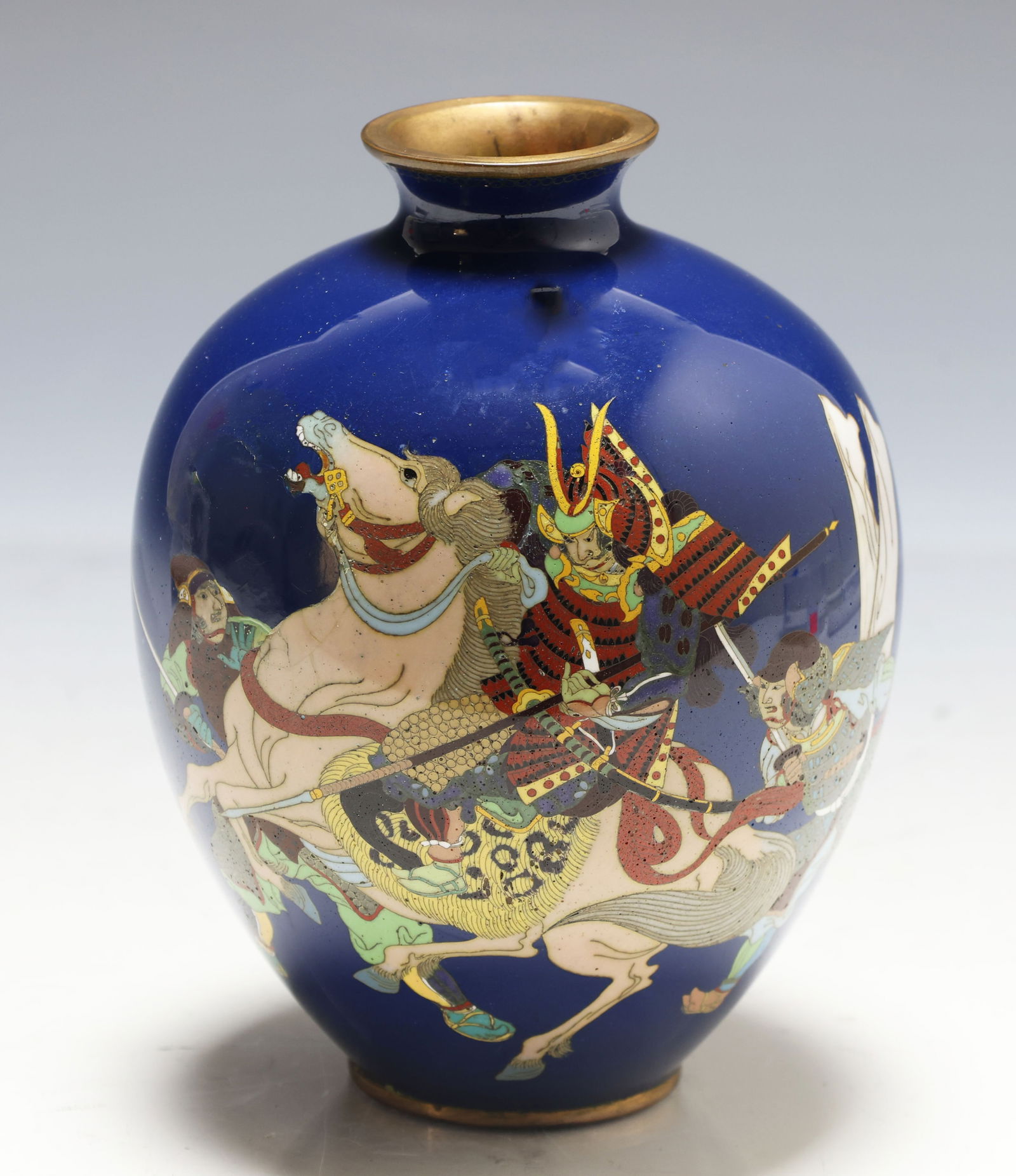 Japanese Cloisonne Vase: Meiji - Taisho era silver wire cloisonne vase decorated with samurai in battle, with a roundel top border, on an azure blue ground. Unmarked. There is an area of restoration and some associated flakin