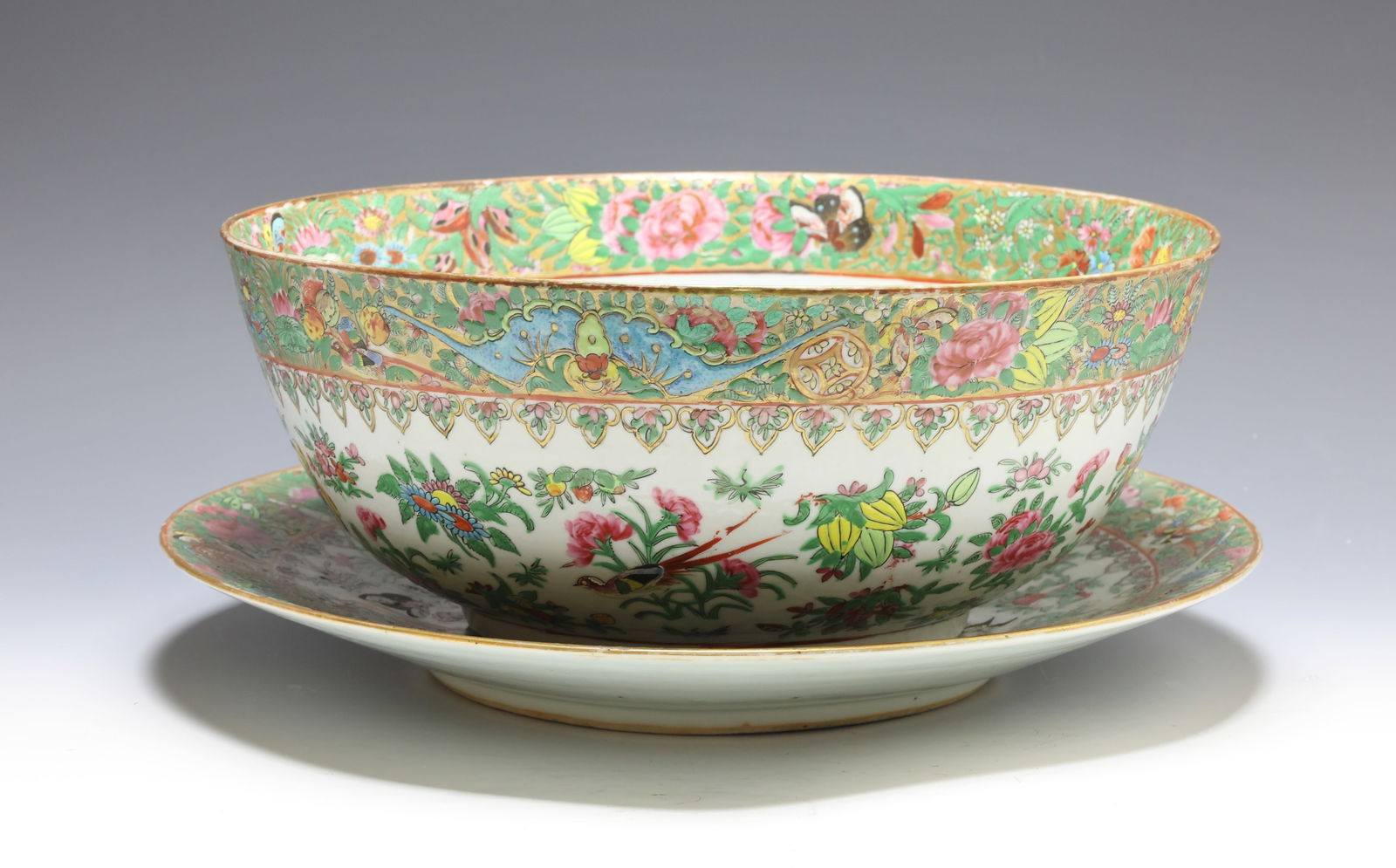 Chinese Rose Medallion Porcelain Punch Bowl and Underplate: Qing era export porcelain punch bowl and underplate, decorated with birds, butterflies, bats, coins, and flowers in a garden setting, with gilt accents. (2) pieces. Bowl 5.5"h x 13.5"w, underplate 2"h