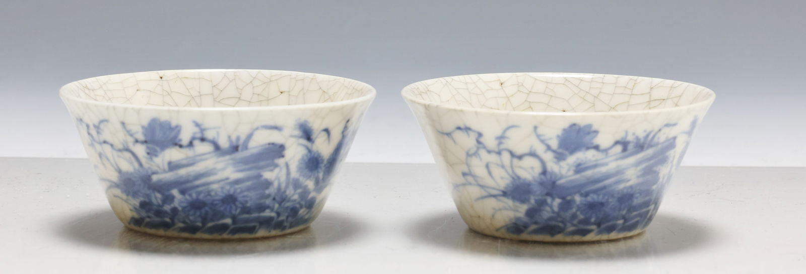 Chinese Porcelain Ruoshen Teacups: Early Qing dynasty pair of blue and white crackle glaze ruoshen cups for the Gungfo tea ceremony, decorated to one side with insects and flowers in a crag, and to the other side with a floral sprig an