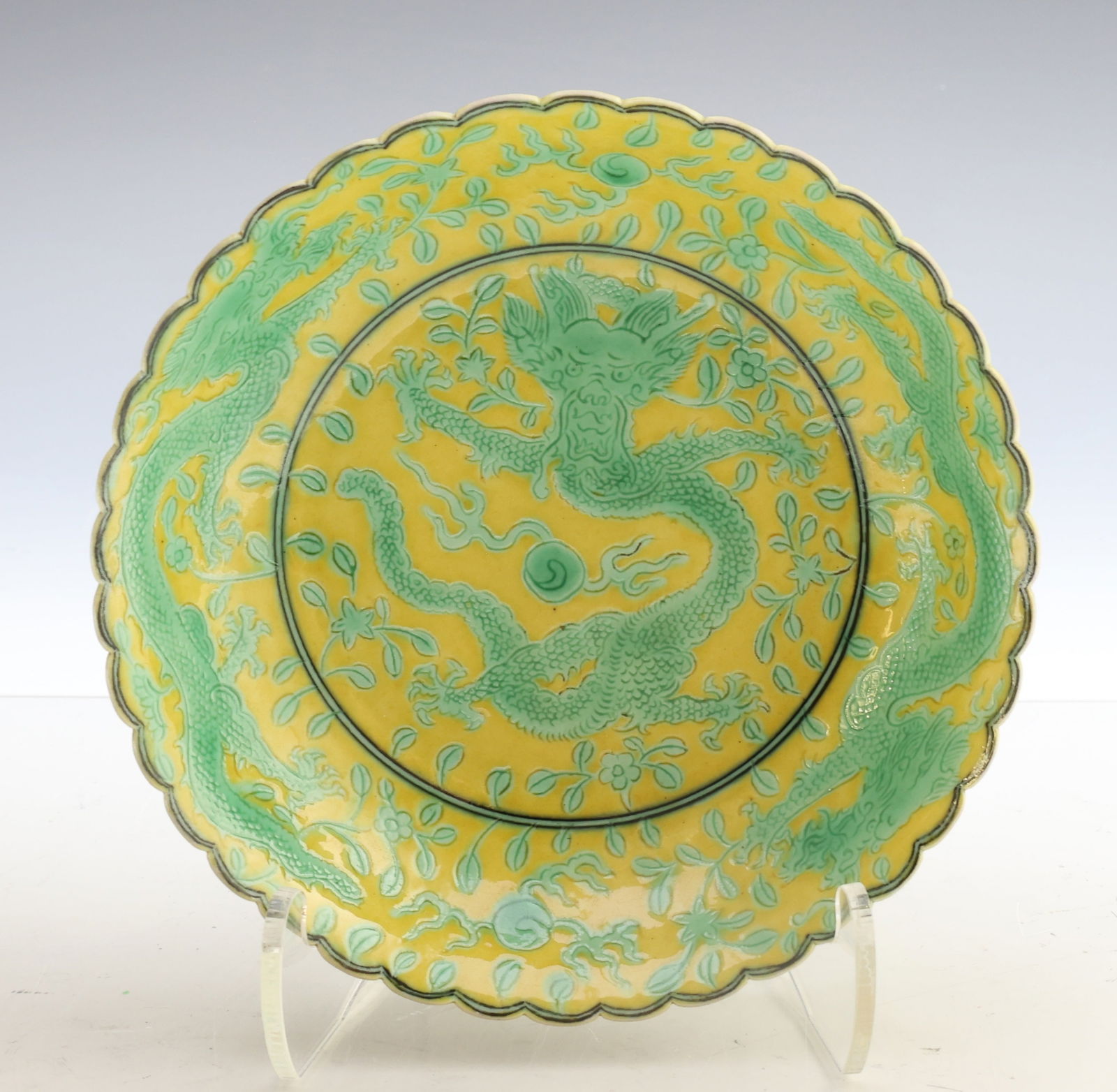 Chinese Yellow Ground Porcelain Dragon Dish: Qing dynasty porcelain dish, Qianlong period (1736–1795), decorated on a yellow ground with green enamels. The dish has a scalloped rim dressed in black and the interior is decorated with a central