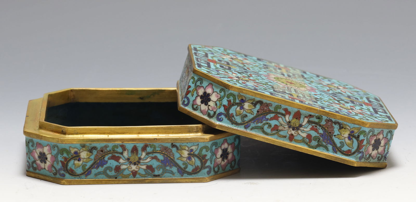 Chinese Cloisonne Enamel Octagonal Box and Cover, Qianlong Mark: Chinese cloisonne enamel octagonal box and cover, turquoise ground with scrolling lotus blossoms and foliate decoration, gilt edged, top centered by a roundel with six character Qianlong mark in seal