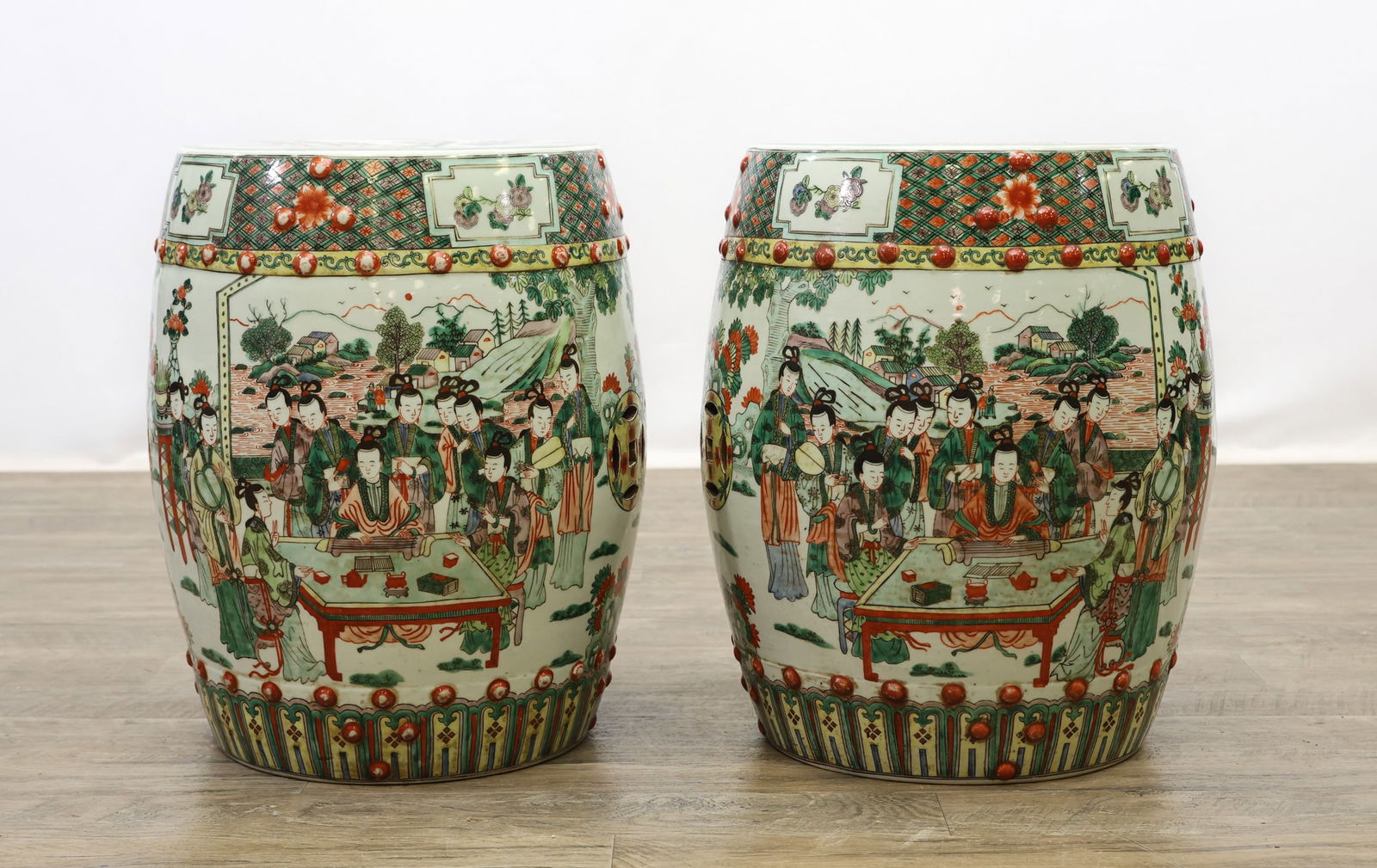 Chinese Porcelain Garden Stools: Qing - Republic era, decorated in famille verte enamels with figural court scenes in landscaped settings, raised iron red bosses, pierced drum form tops, and geometric and floral borders. 17.5"h x 13"