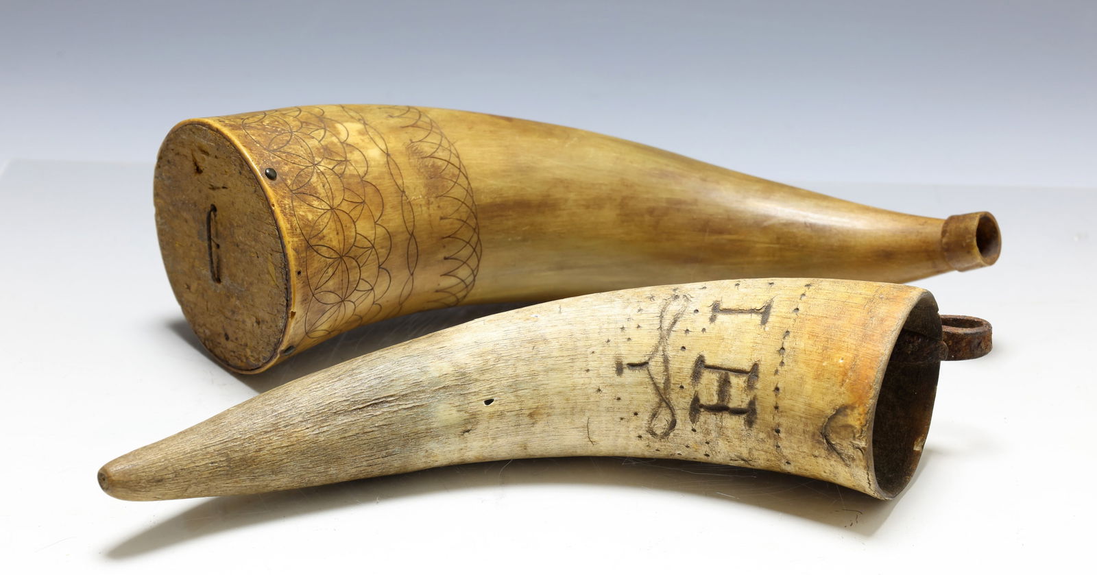 19th century Decorated Horns: Pennsylvania German powder horn with wooden plug, top decorated with bands of compass engraving and dated 1809. Pennsylvania German whetstone holder with wrought iron hook and burned initials "I H"