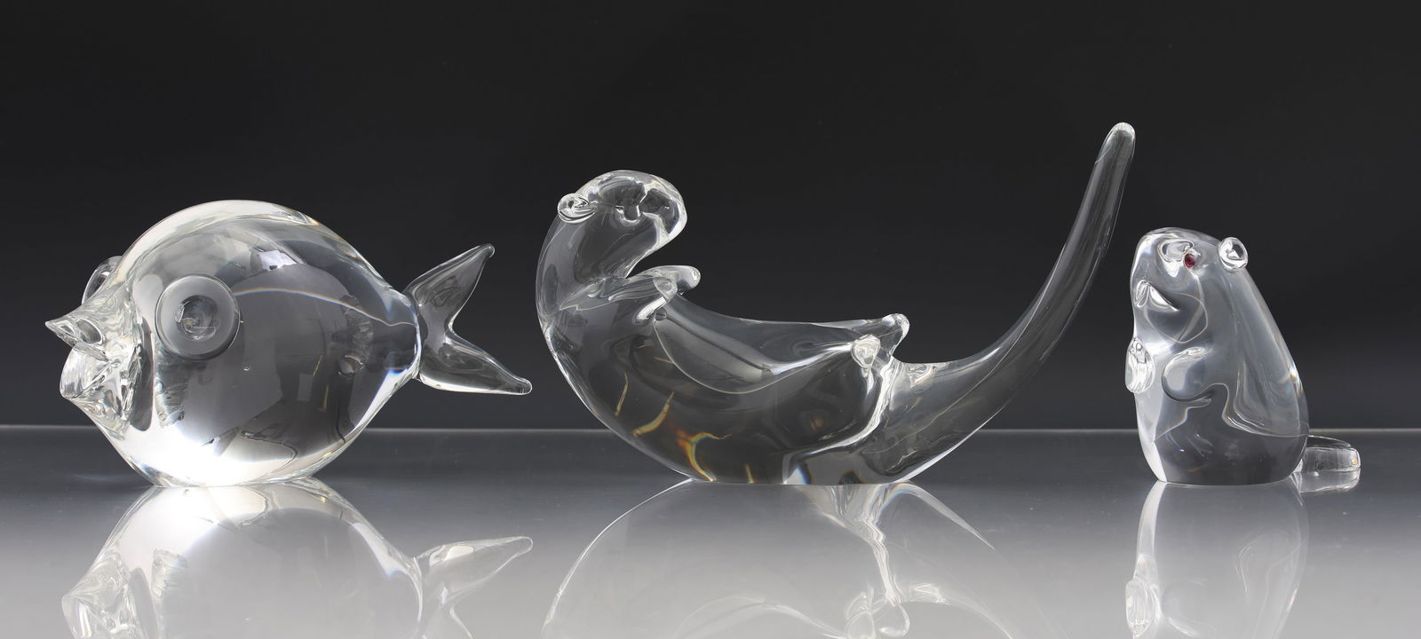Steuben Crystal Aquatic Animal Figurines: Crystal figurines, including "Fish", model no. 8107, 3.75"h x 2.5"w x 7"d, "Sea Otter", model no. 8368, 5"h x 2.75"w x 8"d, and "Beaver with Garnet Eyes - Small/Upright", model no. 8360-9155, 3.5"h x