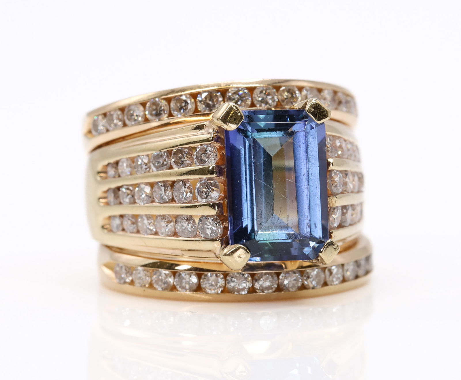 14k YG Tanzanite Diamond Ring: 14k yellow gold ring set with an approximately 4.75 carat emerald cut tanzanite accented by round brilliant cut diamonds totaling approximately 0.60 carats. Size 4 and 5.7dwt.