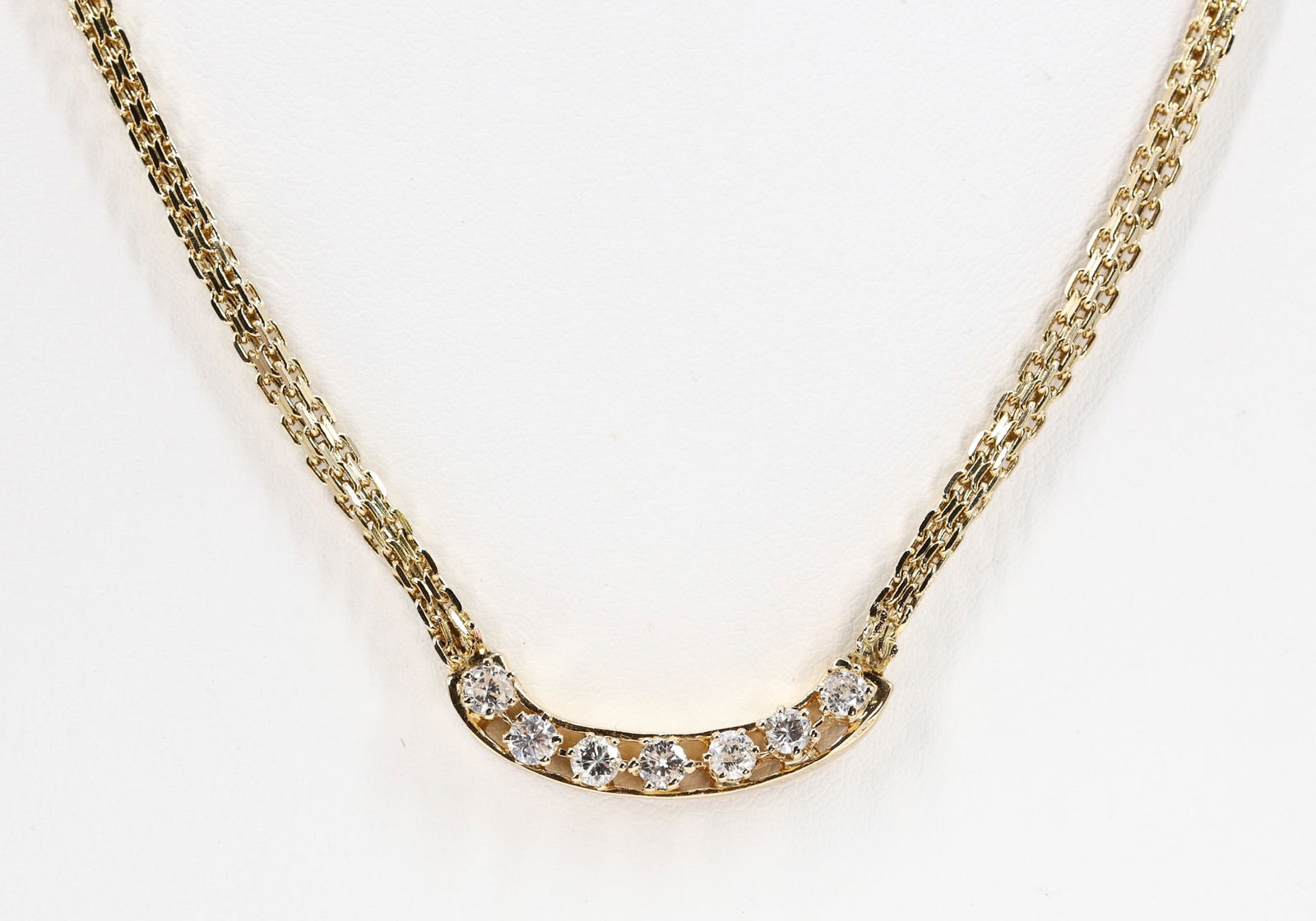 14k YG Diamond Necklace: 14k yellow gold necklace set with (7) round brilliant cut diamonds totaling approximately 0.70 carats in curved bar form, suspended from a Boston link chain. 19" and 12.3 dwt.