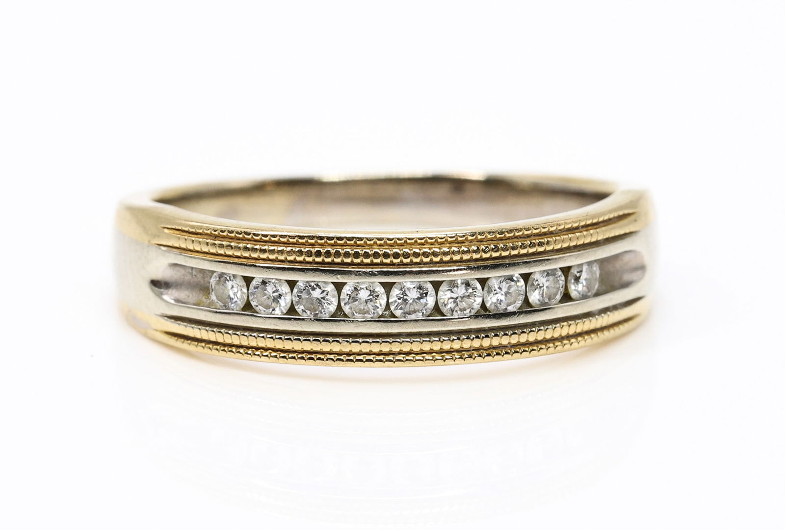 14k YWG Diamond Ring: 14k yellow and white gold band set with channel set round brilliant cut diamonds totaling approximately 0.20 carats. Size 9.5 and 4.1 dwt.