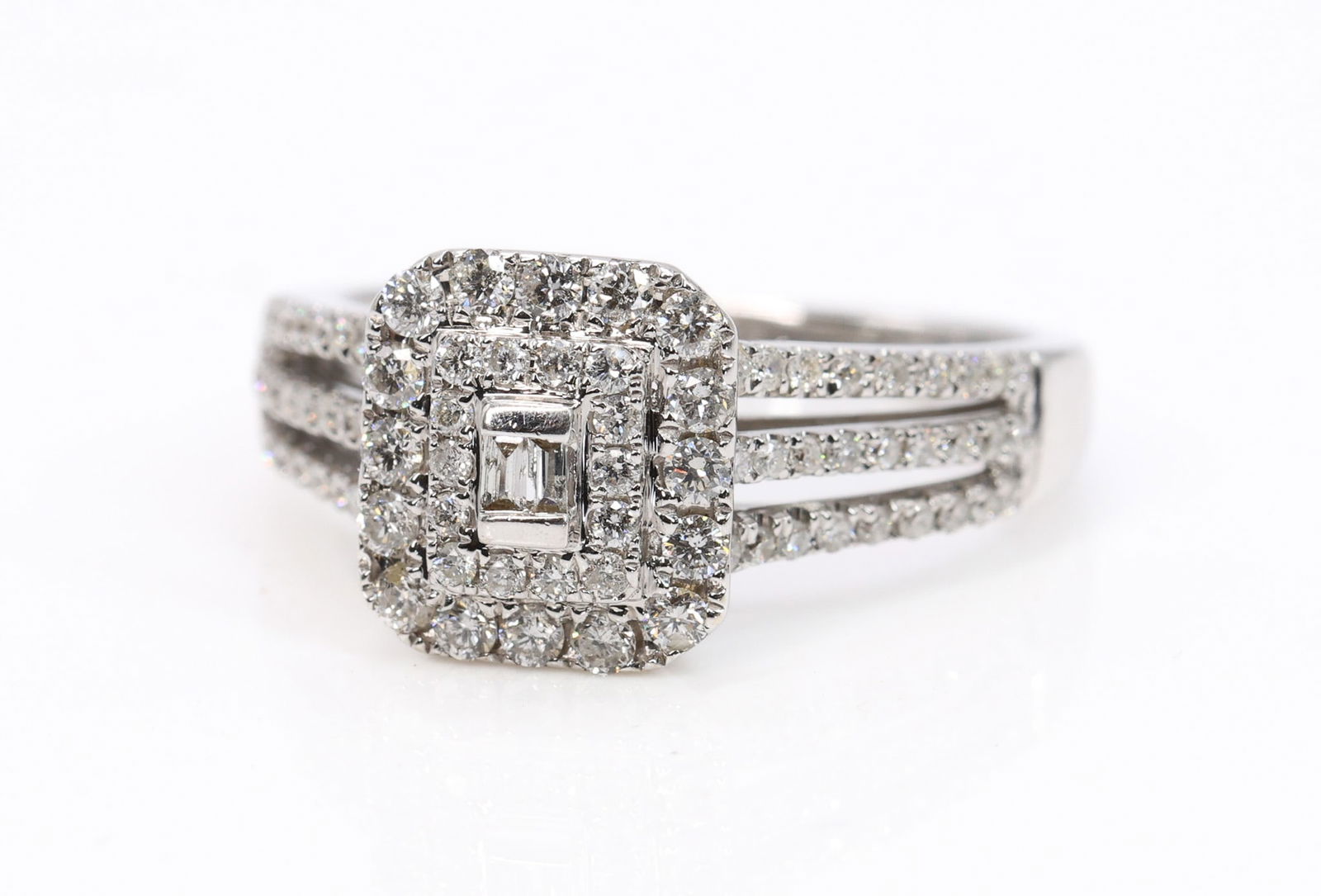 14k YG Diamond Ring: 14k white gold diamond ring set with a baguette diamond center within halos of round brilliant cut diamonds and split shank shoulders accented with round brilliant cut diamonds, approximately 0.75 car