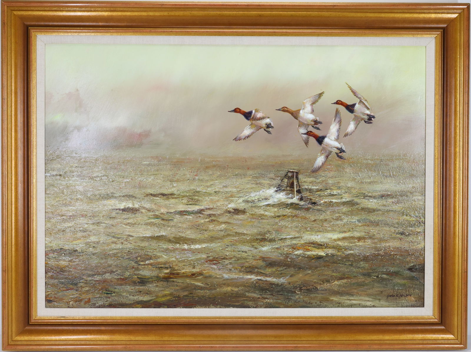 John R. Wilson (20/21st century): Oil on board, SLR. Sporting marine scene with canvasback ducks flying low over open water beside a marker buoy. 31"h x 41"w framed