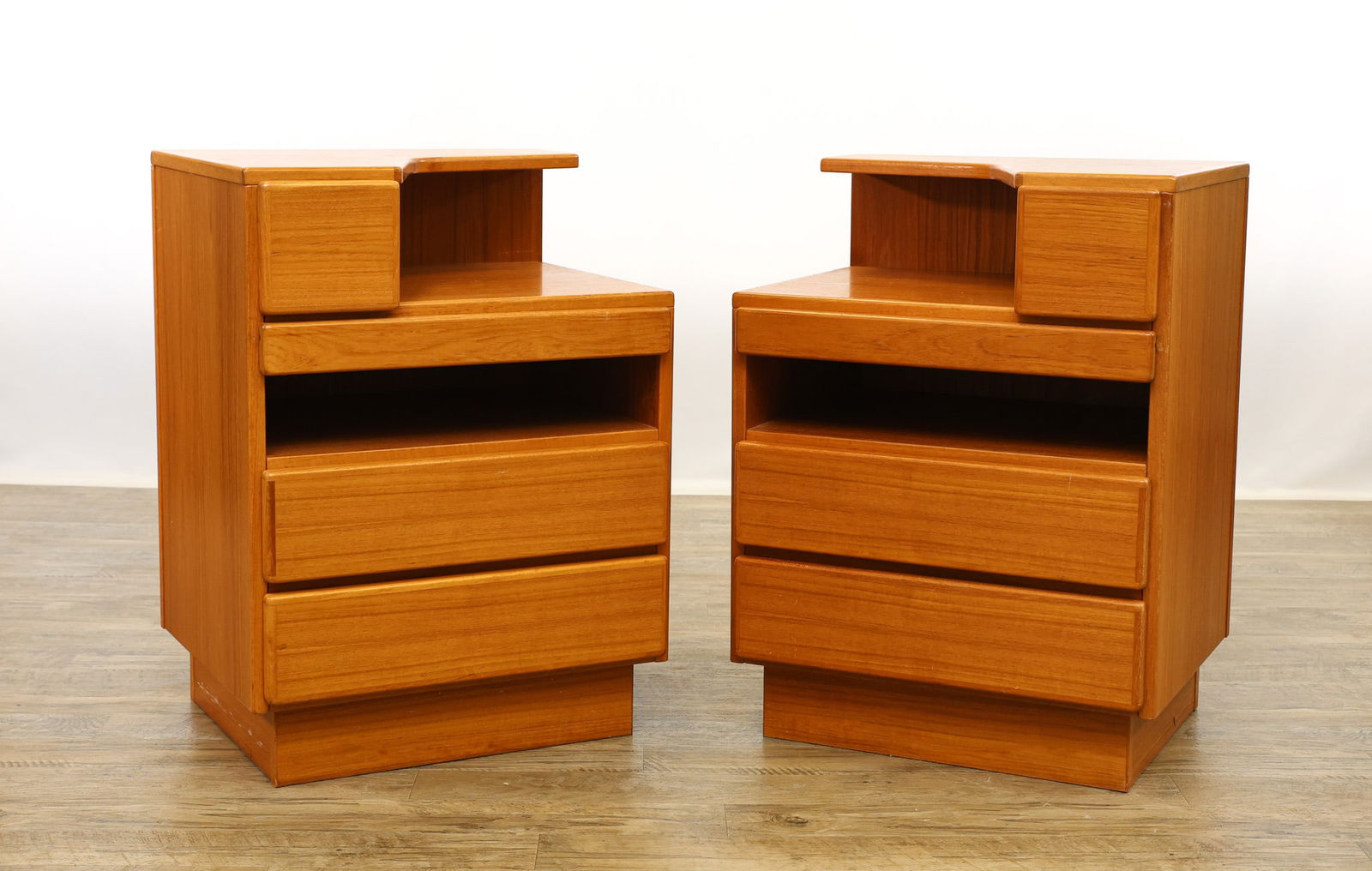 Scan Coll Teak Nightstands: Danish Modern pair of nightstands featuring a two-tiered top surface with a drawer over a pull-out writing surface over open storage over two drawers, raised on plinth bases. Labeled. Originally