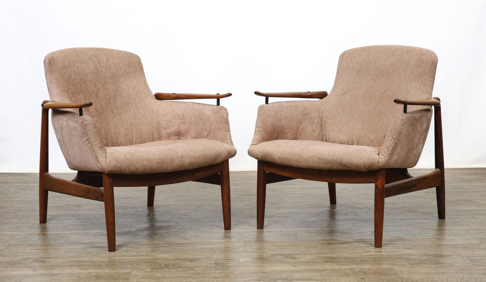 Finn Juhl for Niels Vodder Model 53 Easy Chairs: Danish Modern pair of easy chairs with rosewood frames featuring cigar stiles and front legs, shaped stretchers, sculpted arms, and upholstered floating seats. Both marked to the interior of the rear