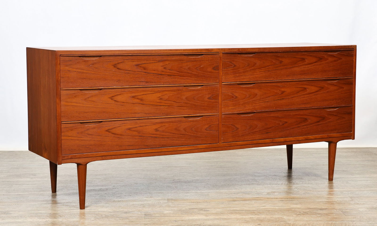 Danish Teak Dresser: Teak dresser with three drawers beside three drawers, with a shaped apron and tapered round legs. Marked Made in Denmark. The back panel shows splits; water stains to one side; some other scattered