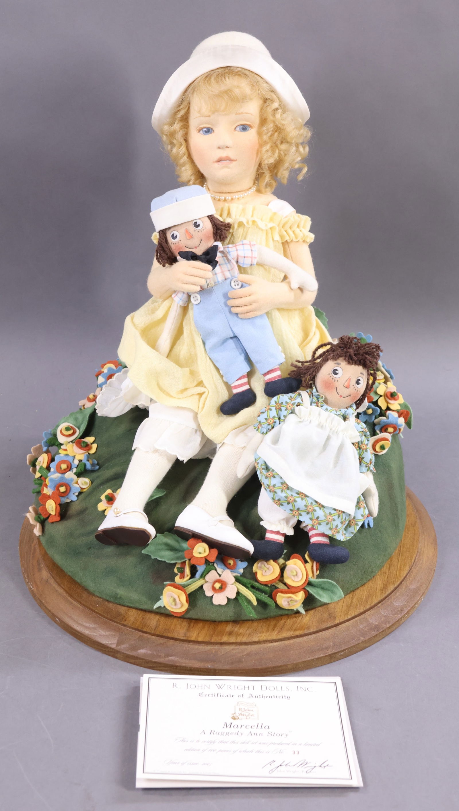 R. JOHN WRIGHT.: LOT. MIB 2005 17" "Marcella", A Raggedy Ann Story. "Marcella" is holding a 6" Raggedy Ann and 6" Raggedy Andy doll. 33/100, COA. Base - is in the OB. They are sitting on a custom-made display base