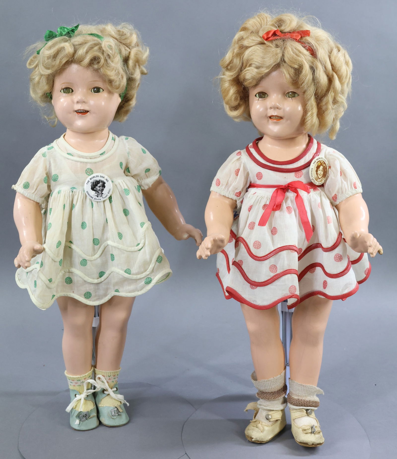 COMPOSITION DOLLS.: Pair of 18" IDEAL "Shirley Temple" dolls dressed in original tagged polka dot dresses. Both have their original honey blonde mohair wigs. Each have a separate teddy, oilcloth shoes. Doll 1) with red p