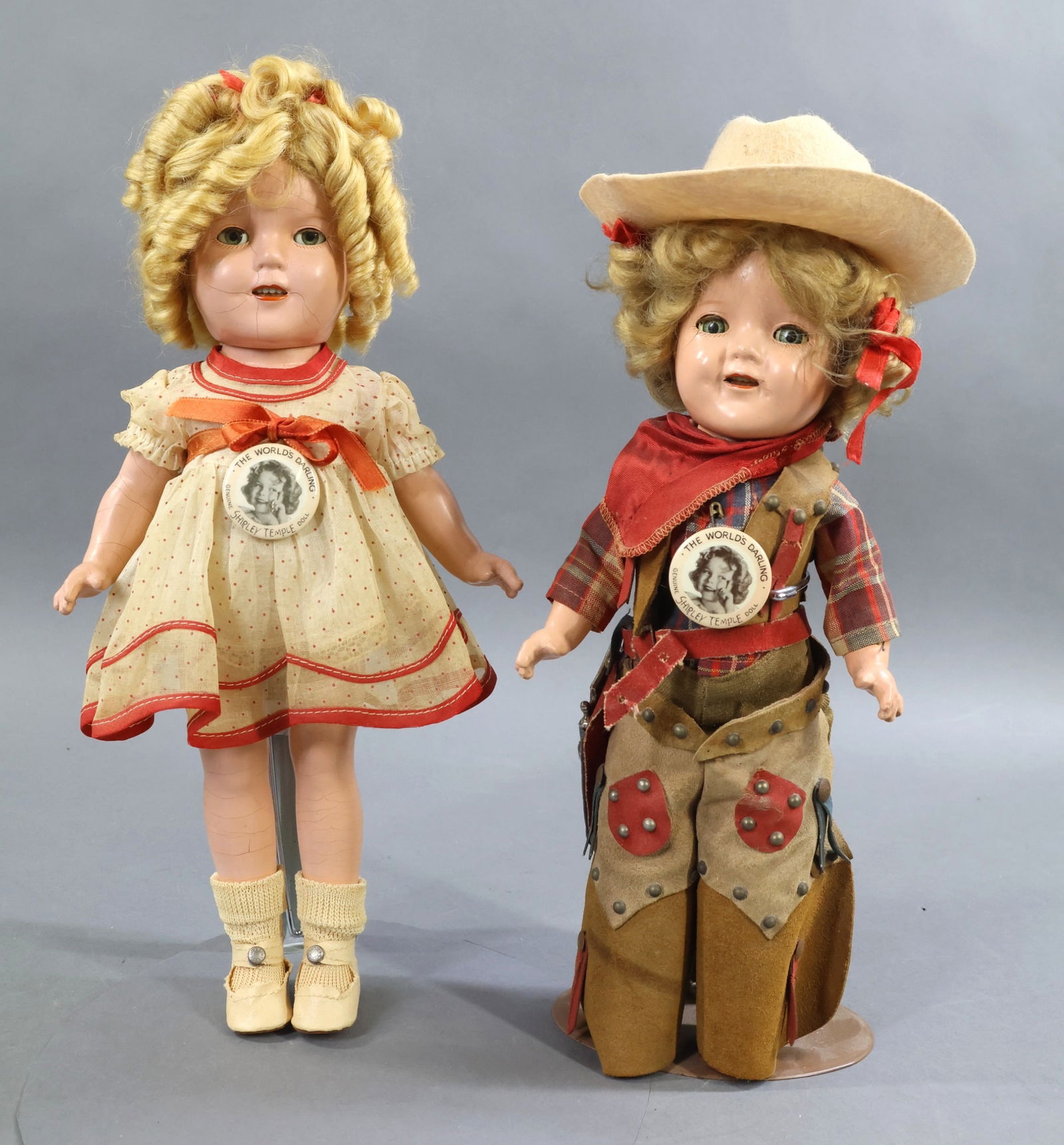 COMPOSITION DOLLS.: Pair of IDEAL "Shirley Temple" dolls dressed in original outfits. Both have their original honey blonde mohair wigs and "The World's Darling" pins. Doll 1) 12" Doll dressed in 1936 "Texas Ranger" outf