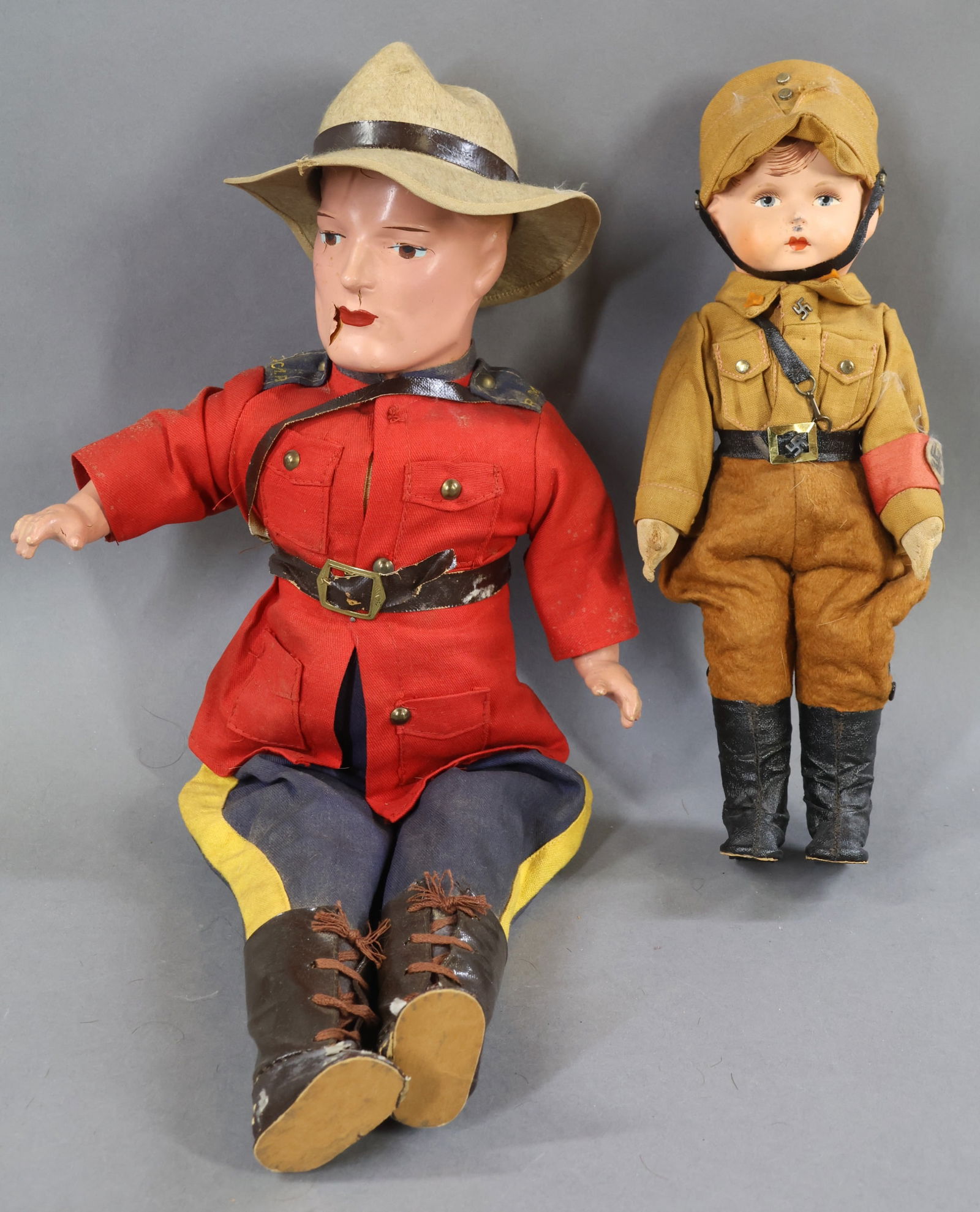 COMPOSITION DOLLS.: Pair of male dolls dressed in original costumes. Both dolls have painted features and hair. Cloth bodies. Doll 1) 16" RELIABLE CANADA R.C.M.P. (Royal Canadian Mounted Police) Composition lower arms.