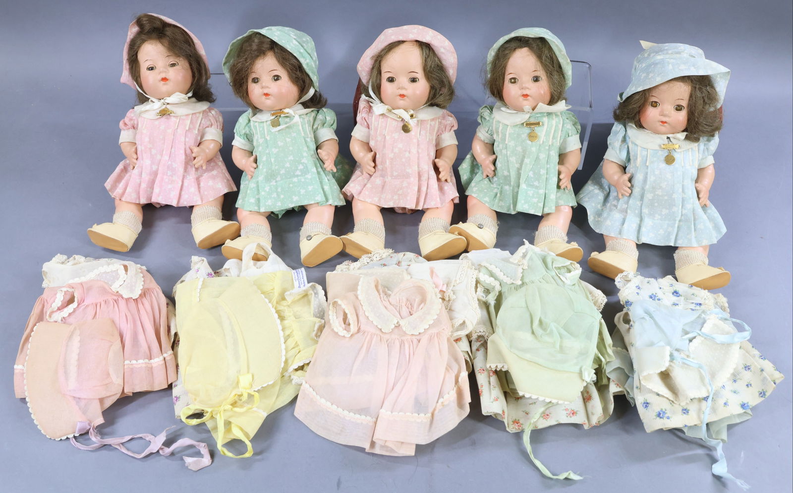 COMPOSITION DOLLS.: SET of MADAME ALEXANDER 11" "Dionne Quintuplet" toddler dolls in their OB. Extra clothing with each doll. Each doll has a brown HH wig, sleep eyes. They are each wearing a tagged cotton floral print