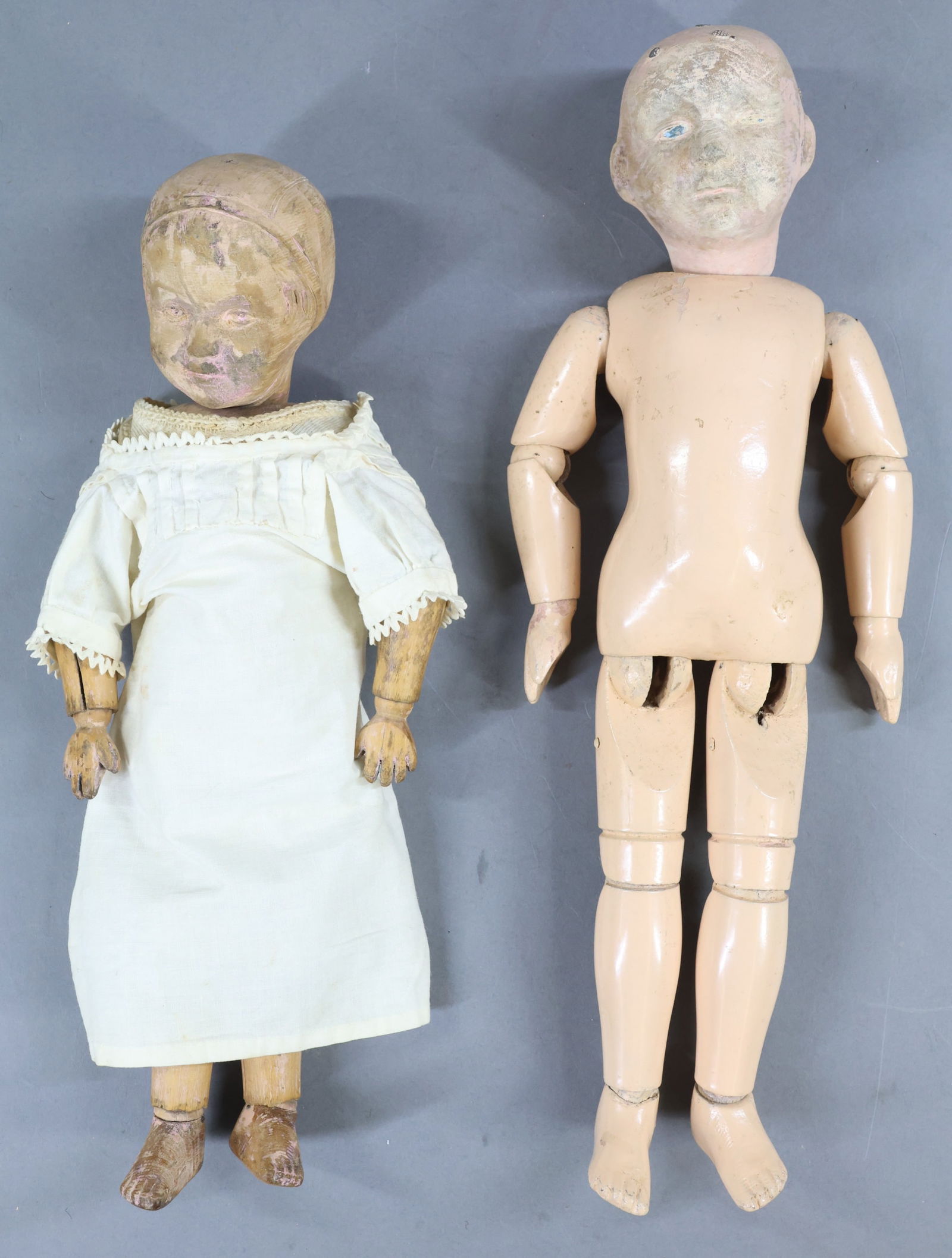 SCHOENHUT.: Pair of carved head female dolls. Doll 1) 14" Model No. 106 Bonnet Head doll. Incised mark on back of torso. Some antique clothing including a union suit. No shoes. Condition: all paint is missing