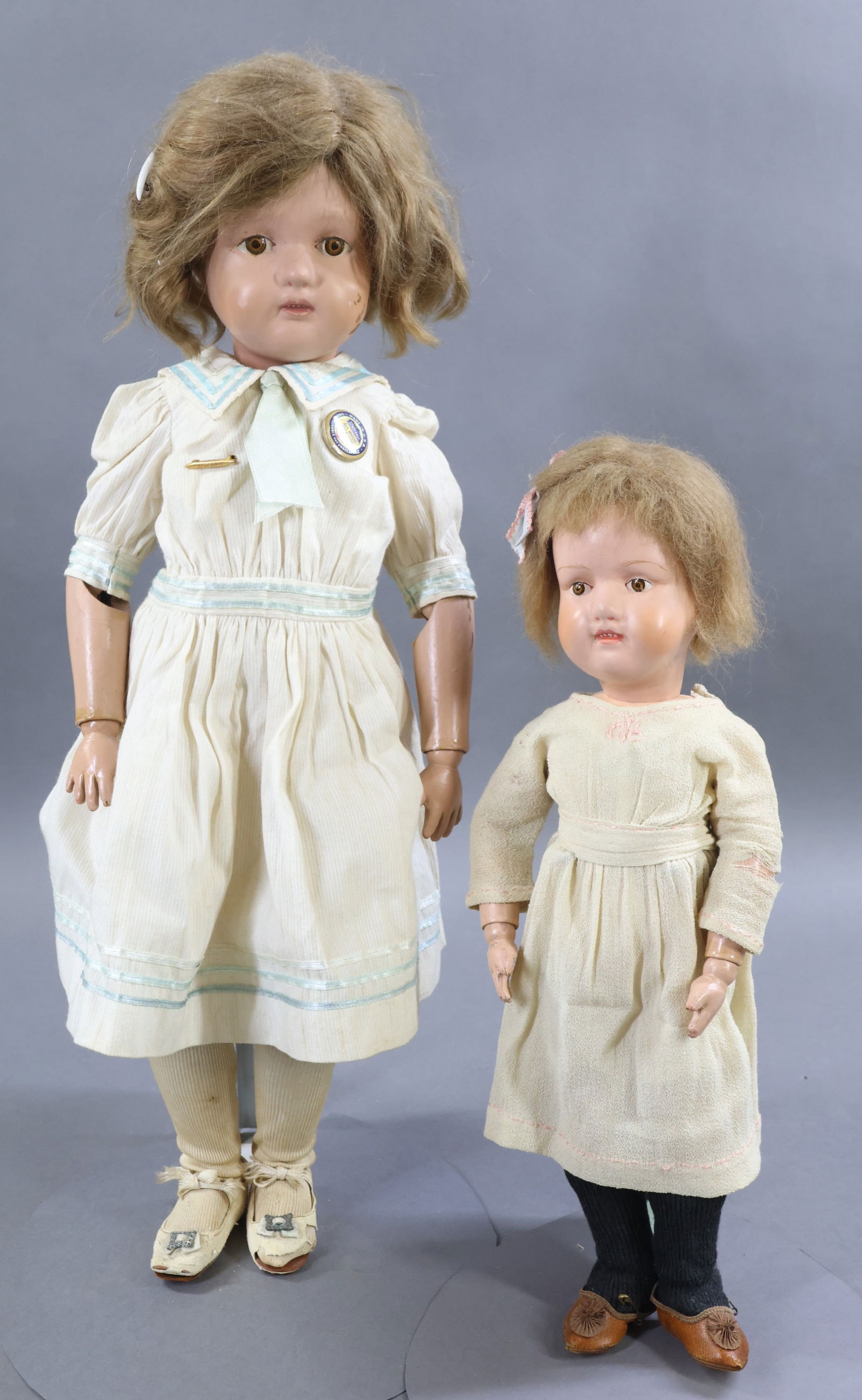 SCHOENHUT.: Pair of "Miss Dolly" Model No. 316 dolls. Both dolls have brown decal eyes. They both have the oval decals on the back of the torsos. Doll 1) 22" with original brown mohair wig. Dressed in vintage