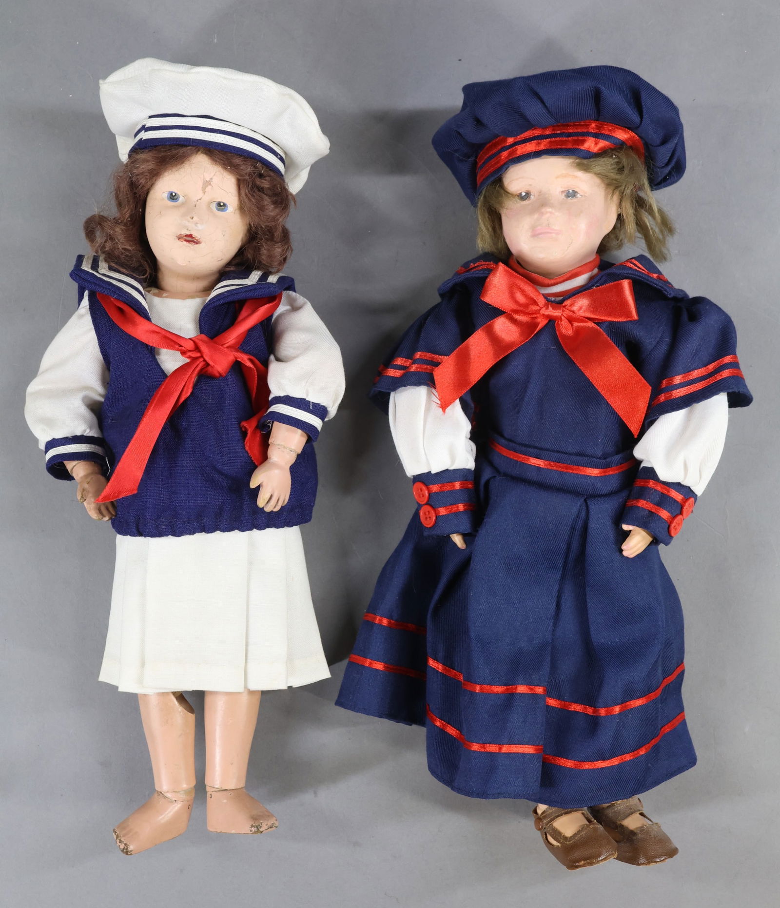 SCHOENHUT.: Pair of wigged female dolls. Both dolls have intaglio eyes, replaced brown mohair wigs. They are both dressed in reproduction sailor outfits. Doll 1) 14" Model No. 312 with brown eyes. She has brown