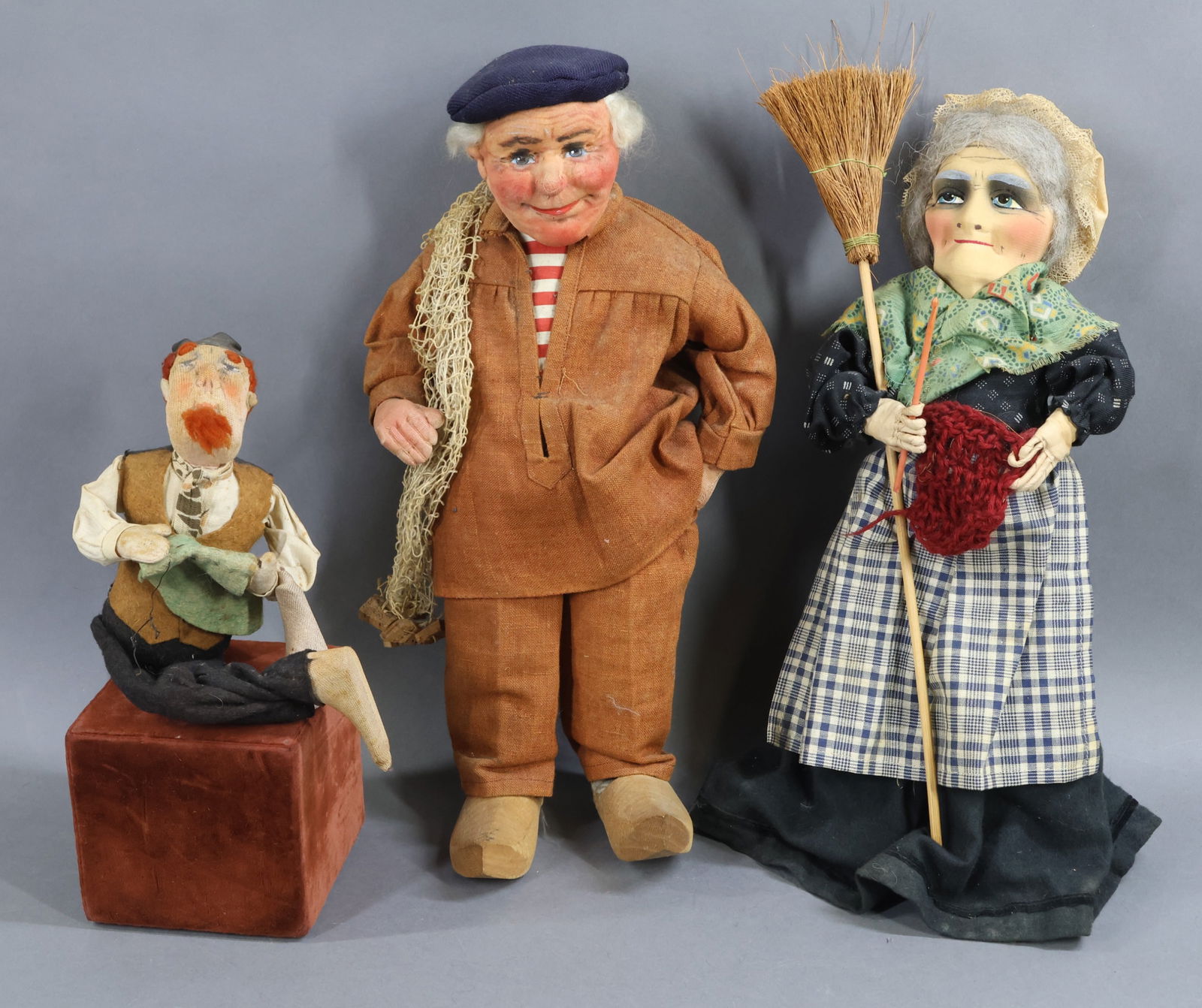 CLOTH DOLLS.: LOT of (3) all original dolls. 6 1/2" (Sitting) 1927 K * R Stockinette character doll. 15" Mask face woman holding broom and knitting. She is wearing clogs. (These are usually French.) 15" Yvonne Spag