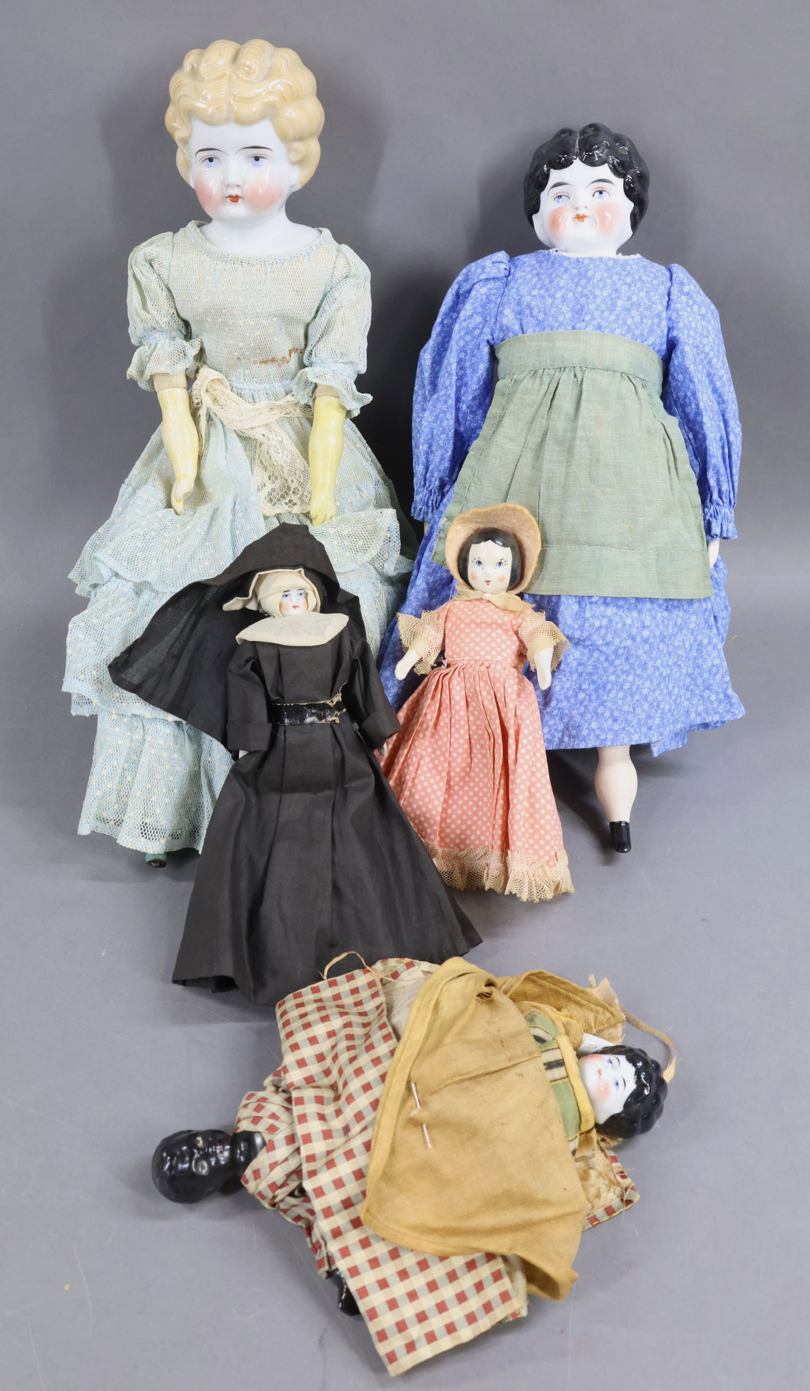 CHINA DOLLS.: LOT of (5) antique/vintage dolls. (2) Low brows - 16" antique with molded shirt waist, has black hair, blue eyes. Newer body with reproduction lower limbs. Newer clothing. 18" Antique with blonde hair