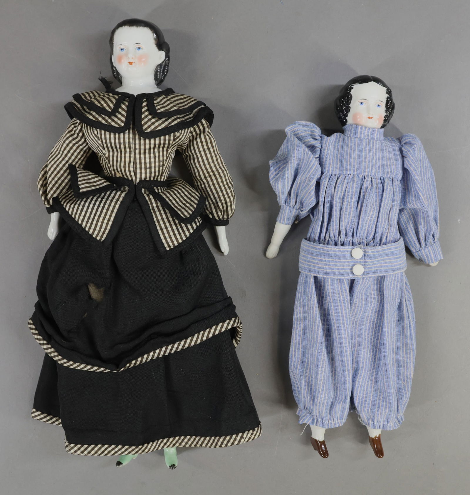 CHINA DOLLS.: Pair of antique dolls with black hair, painted blue eyes. Both have their original cloth bodies, china lower arms and legs with painted heeled shoes. Both are dressed in replaced clothing. Doll 1) 12
