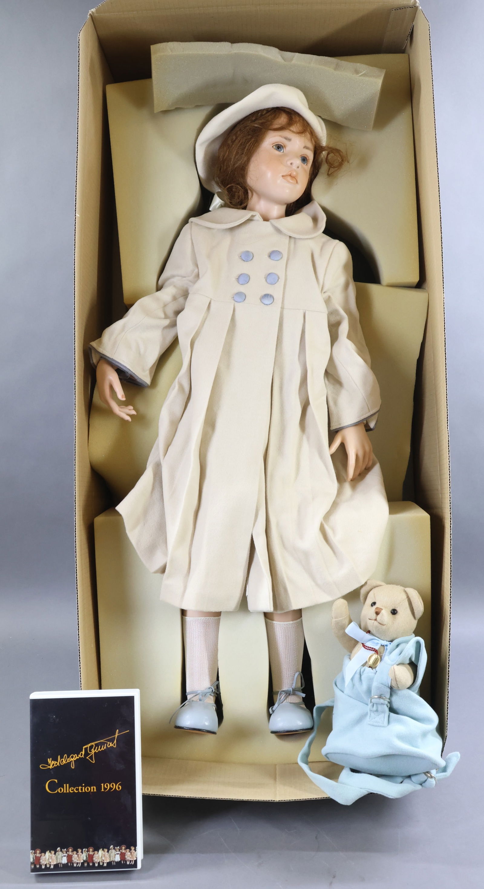 CONTEMPORARY ARTIST DOLLS.: MIB 33" 1996 "Fleurie" doll by artist HILDEGARD GUNZEL. Wax over porcelain. Human hair wig, glass eyes. Dressed in beautiful clothing, leather shoes. She is holding her tagged 9" plush bear in