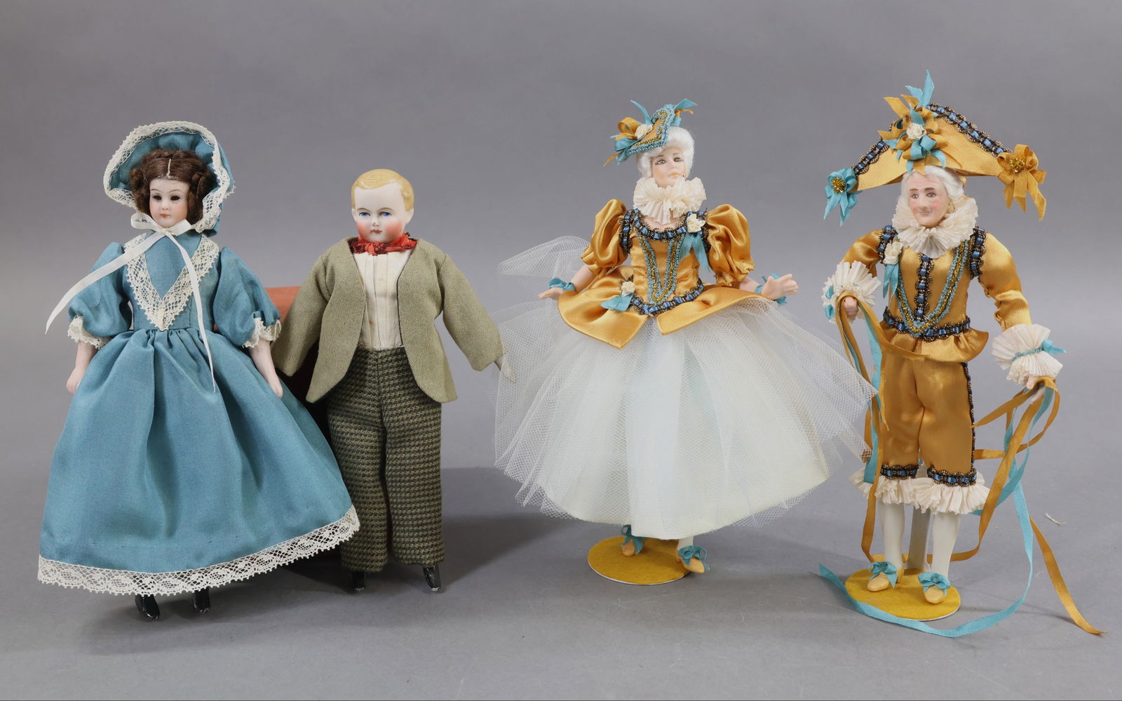 MINIATURES - DOLLS.: LOT of (4) bisque head dolls. (2) Antique - 7" S & H 1160 "Little Women" type doll with glass eyes, mohair wig. Cloth body, bisque lower limbs. Redressed in silk outfit. 6 1/2" Unmarked male doll with