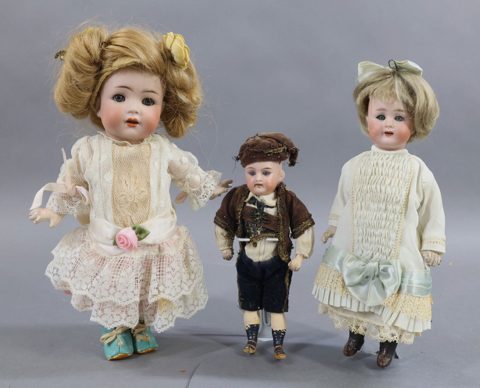 BISQUE DOLLS, 12" UNDER.: LOT of (3) antique German dolls. All of the dolls have blue eyes, open mouths, 5 pc. papier mache bodies. The (2) girls have been attractively redressed. The boy appears to be all original. Doll 1) 9"