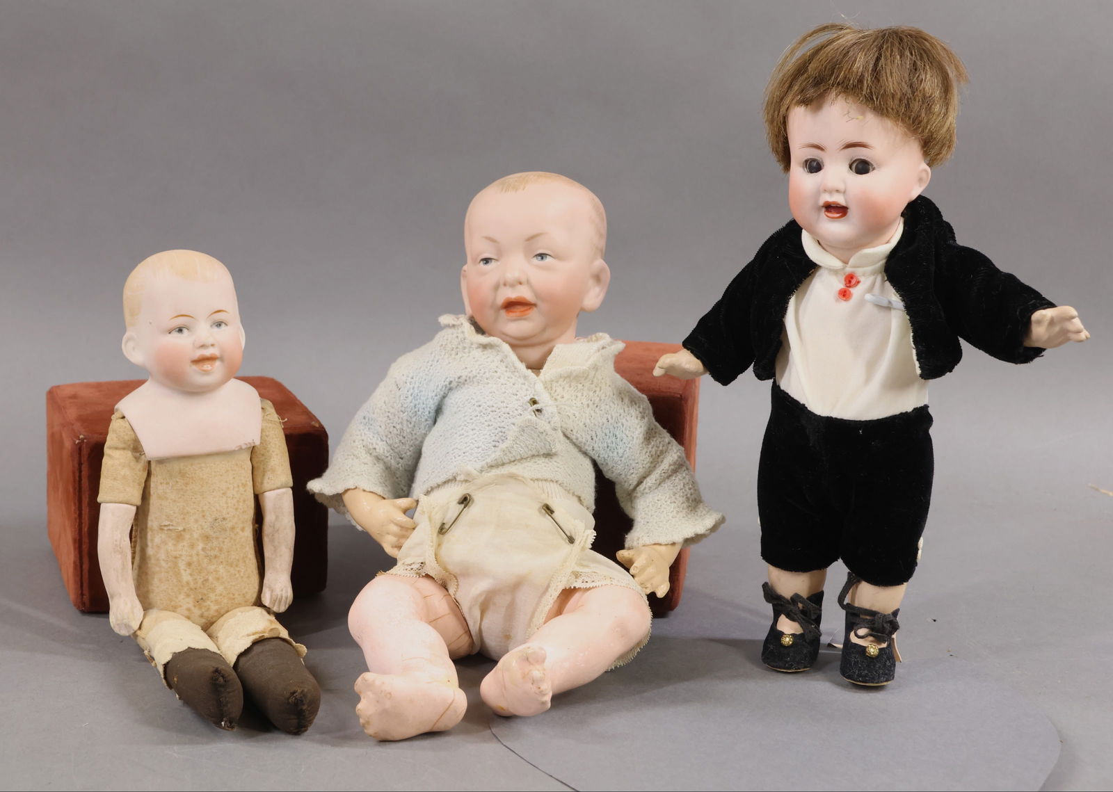 BISQUE DOLLS, 12" UNDER.: LOT of (3) antique German character dolls. All of them appear to be male dolls. Doll 1) 9" ABG 1367/23 with brown sleep eyes, open mouth, brown HH wig. 5 Pc. papier mache toddler body. Dressed in