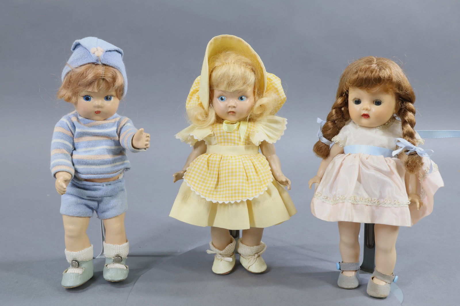 1940's-1960's DOLLS.: LOT of (3) 8" dolls. VOGUE composition 1937-1948 "Toddles" boy doll. Marked on back VOGUE. Painted blue eyes, honey blonde mohair wig. Dressed in tagged outfit, pale blue oilcloth center snap shoes.
