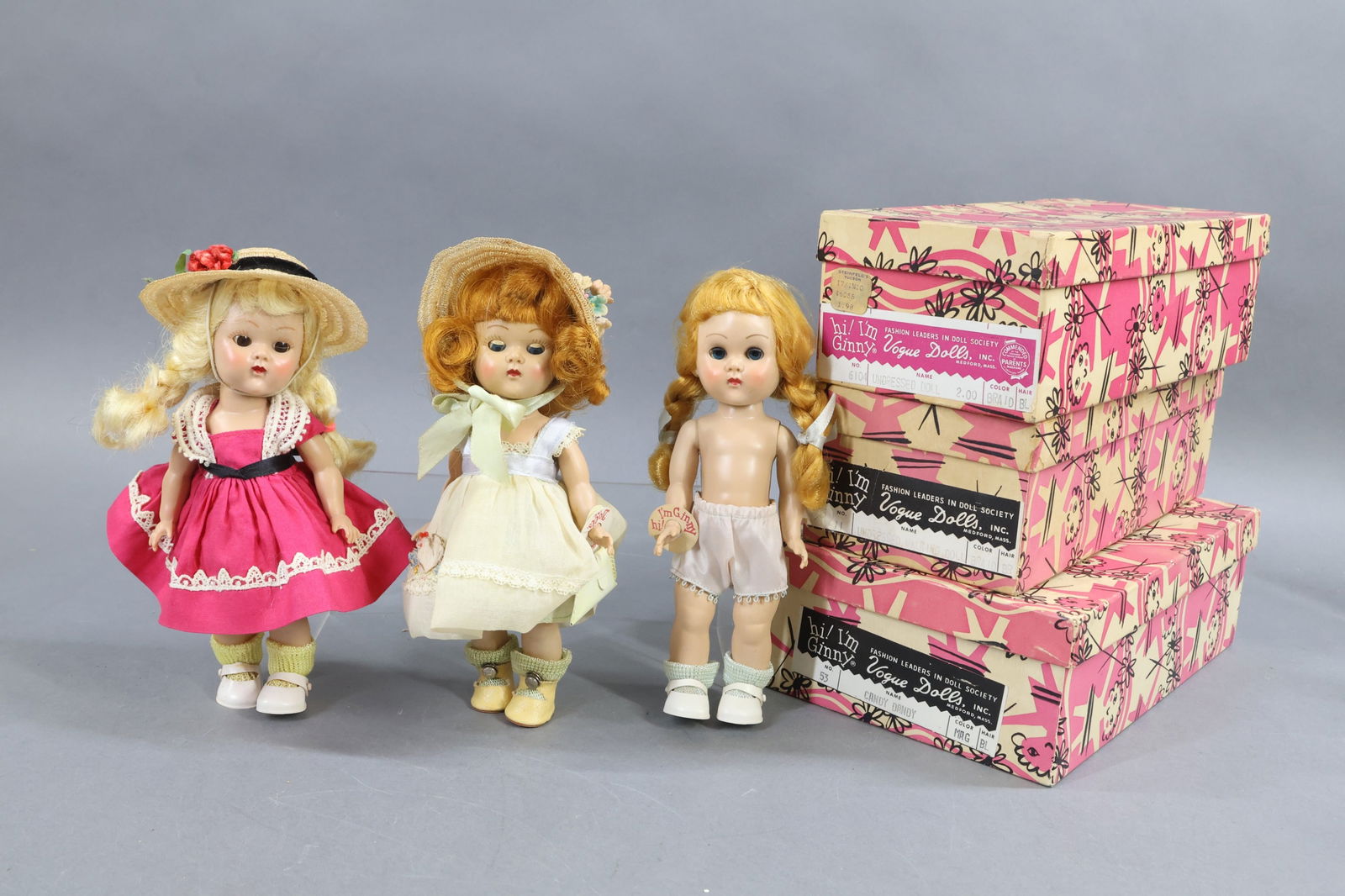 1940's-1960's DOLLS.: LOT of (3) 8" 1954 VOGUE "Ginny" painted lash walking dolls. All (3) are in an OB. Doll 1) Box end reads: 53, "Candy Dandy" Mag, BL. She has blonde braids, dressed in tagged magenta dress with