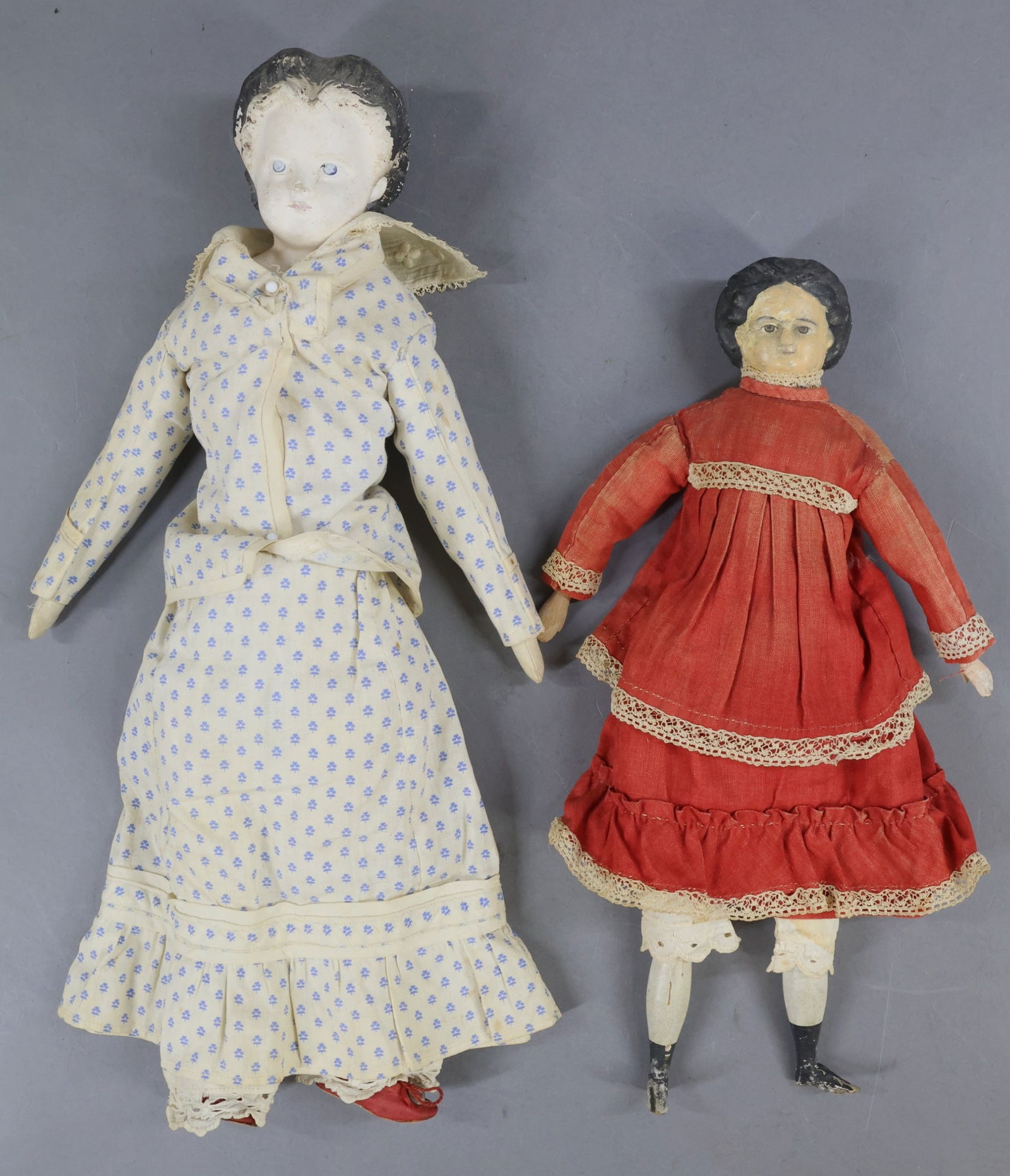 PAPIER MACHE DOLLS.: Pair of unmarked dolls. Both dolls have black center part hair, painted eyes. They are both wearing antique cotton outfits and underwear. Doll 1) 12 1/2" has grey eyes. Cloth body with wooden lower