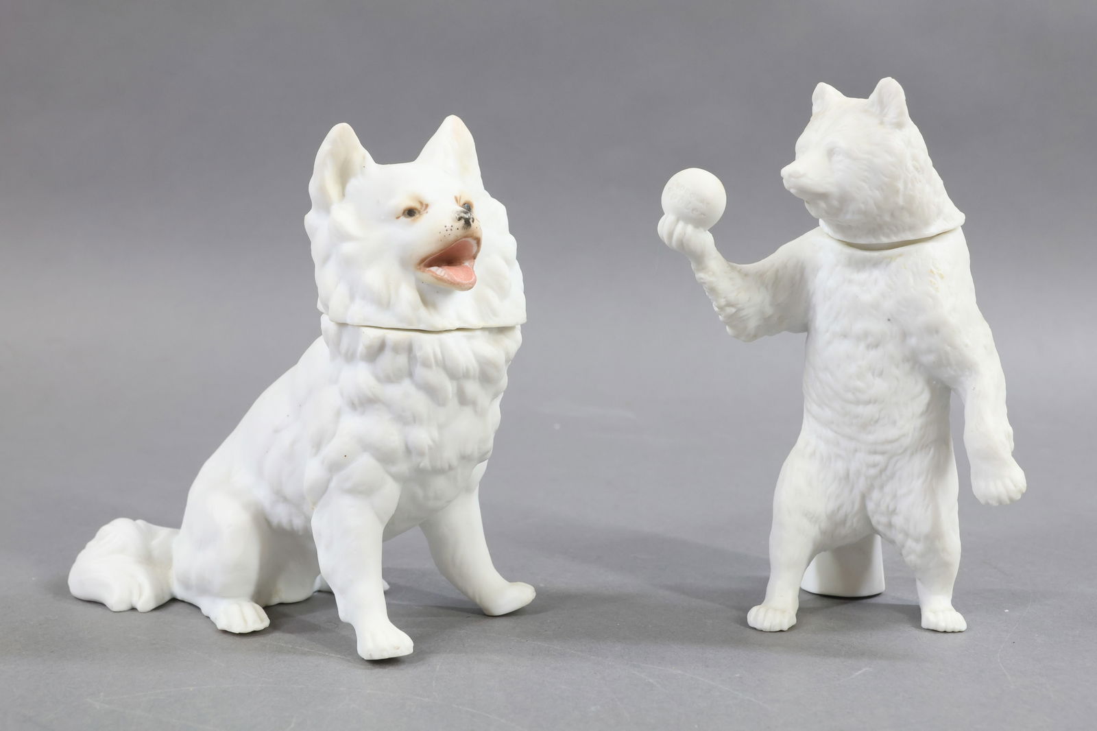 HOLIDAY/NOVELTIES.: NOVELTY. Pair of antique German white bisque animal Candy Containers. 5 1/4" Sitting Dog incised 646 on bottom. Painted eyes, nose and mouth area only. Condition: kiln crack under right front leg.