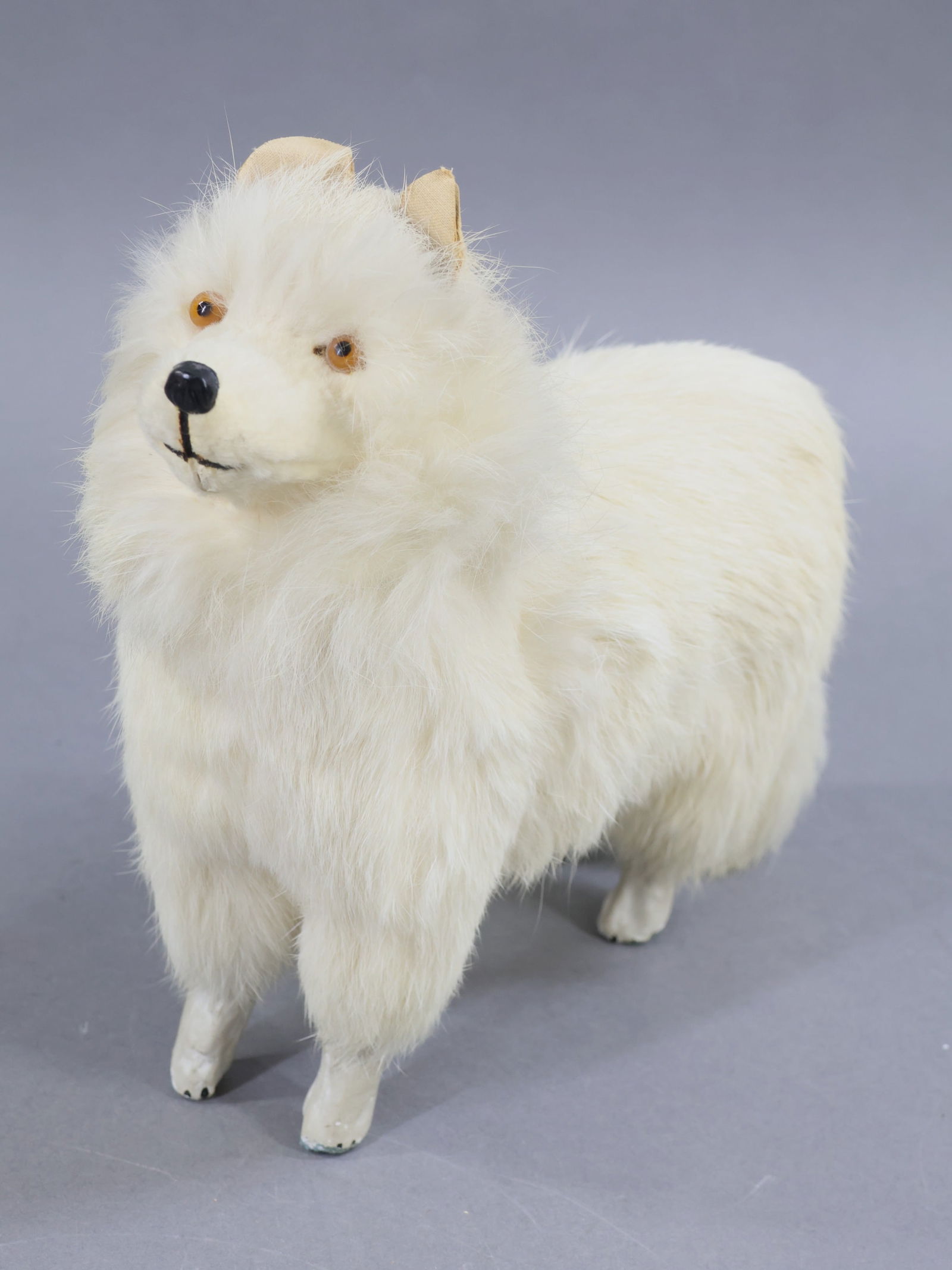 HOLIDAY/NOVELTIES.: NOVELTY. 9 1/2" L x 8" T Antique German white fur covered papier mache Dog Candy Container. Amber glass eyes. Painted nose and mouth. Painted lower legs. Condition: age wear on cloth covered paper