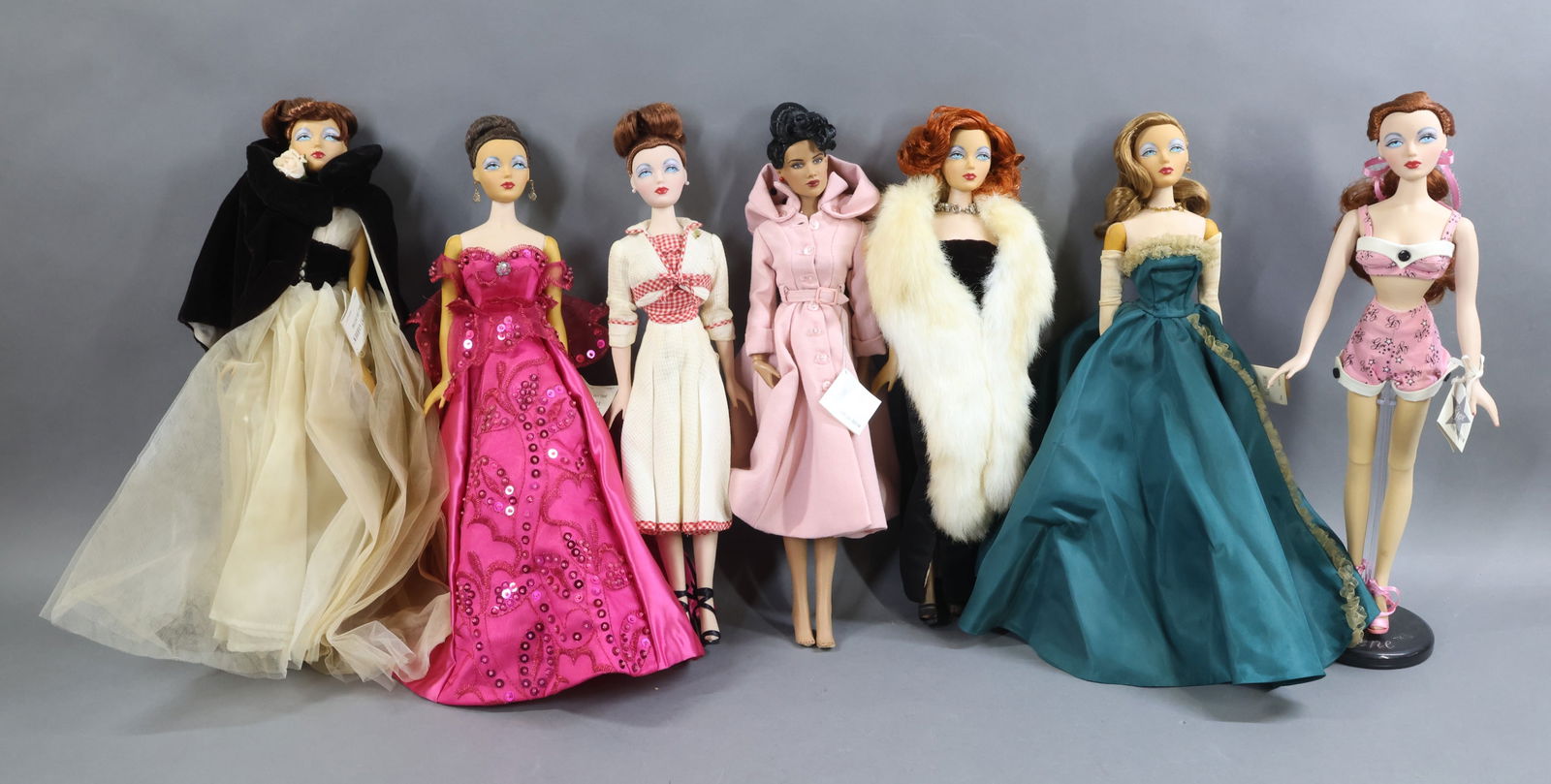 CONTEMPORARY ARTIST DOLLS.: LOT of Mel Odom's GENE. (6) GENE dolls and (1) Tonner Black doll. Tagged GENE - "Simply Gene" (pink). Tonner - Black doll (marked Tribune Media Services) in tagged GENE "Rain Song" outfit (no shoes).