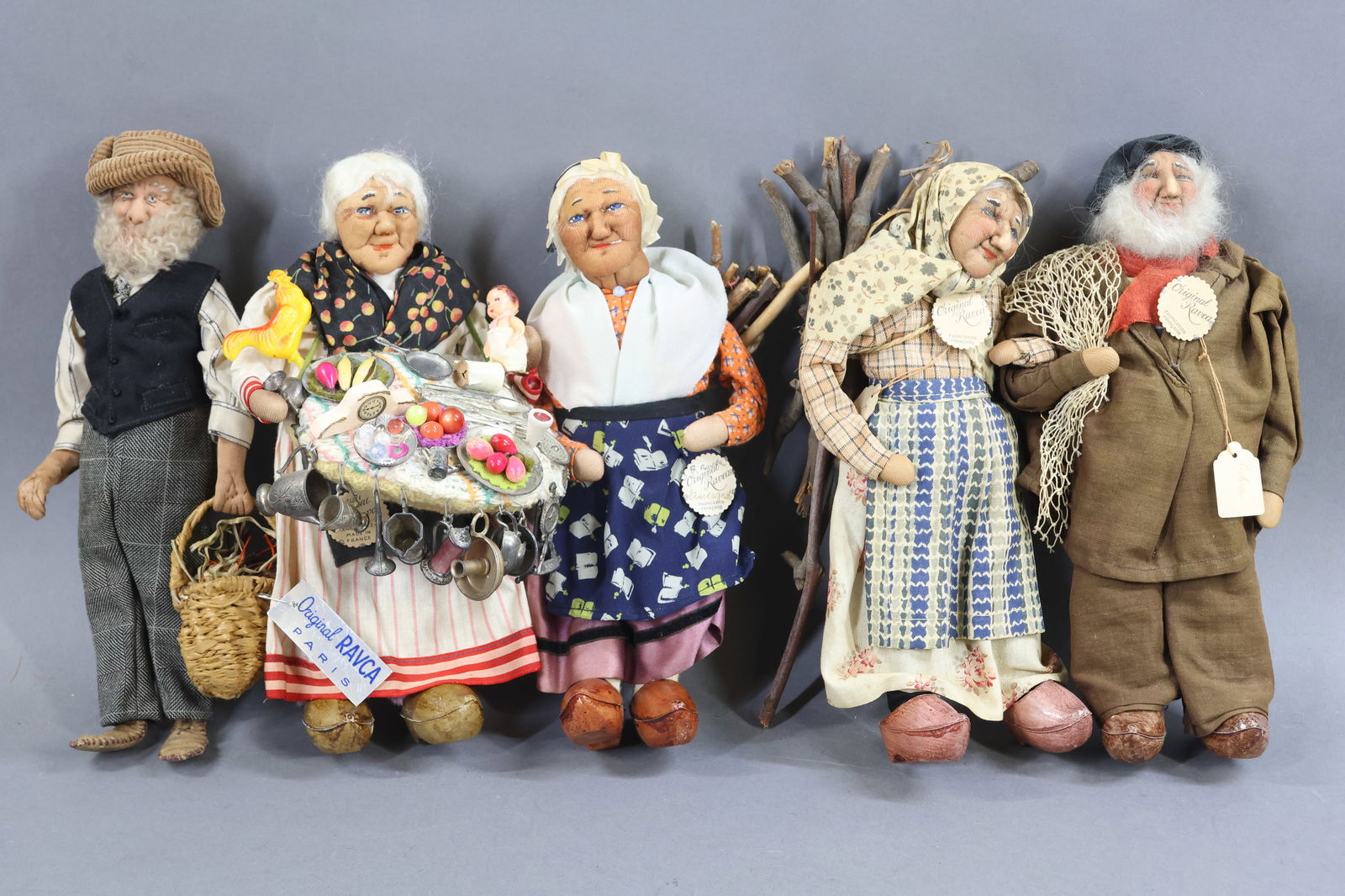 RAVCA.: LOT of (5) 9" Elderly Bernard Ravca dolls. All are marked with the RAVCA medallions. Man carrying basket. Woman carrying wood on her back. Woman carrying larger amount of wood on her back and tagged "