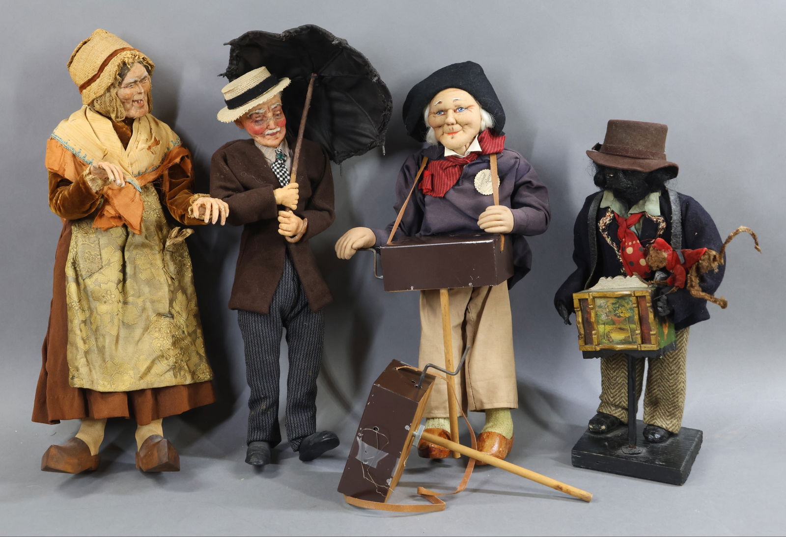 RAVCA/TYPE & OTHER.: LOT. (3) Bernard Ravca/type dolls. 15 1/2" Elderly man holding an umbrella (unmarked). Very dapper with his glass eye pcs., a "straw boater", checkerboard tie and green jewel pin. 16" Elderly Female w