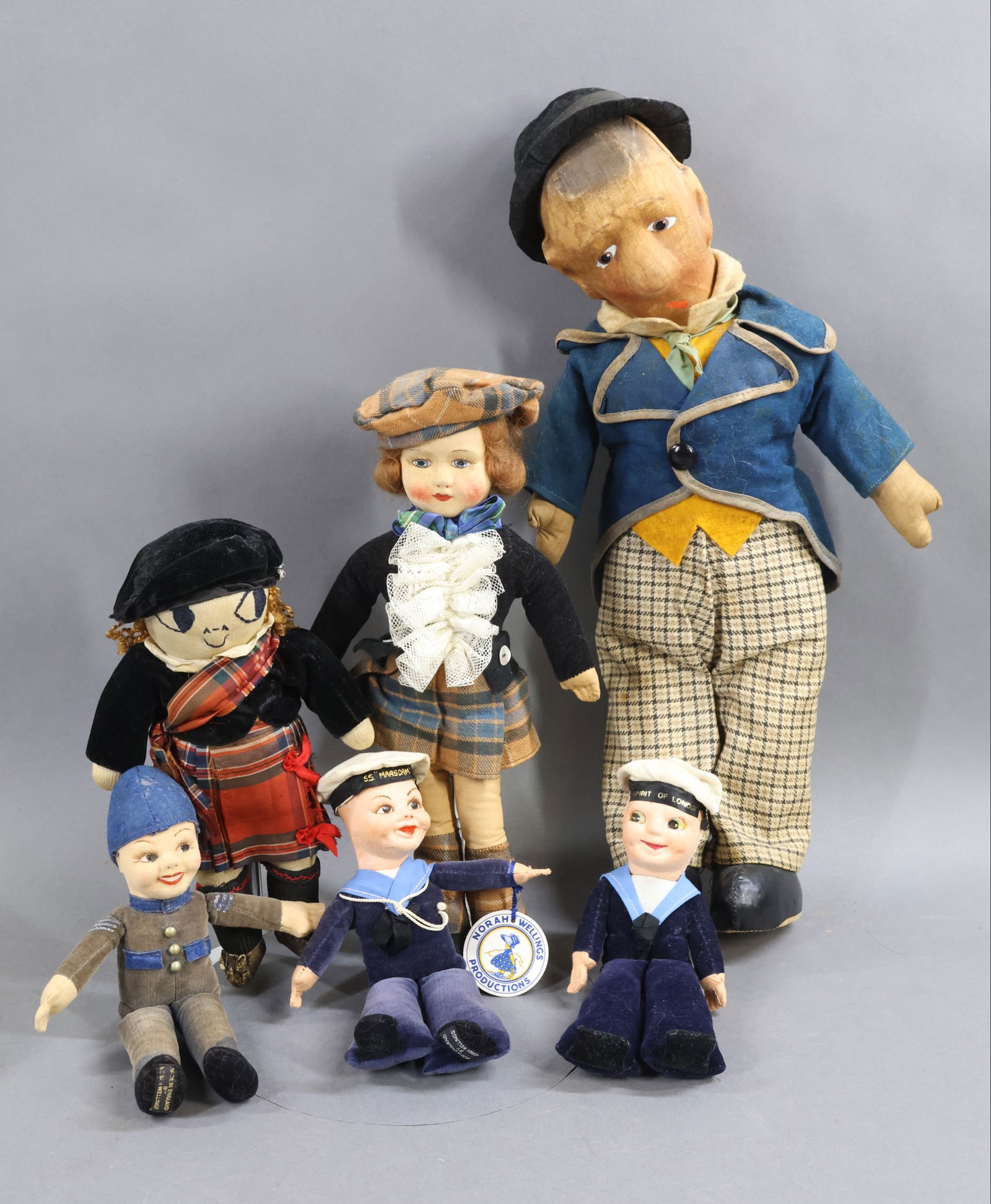 CLOTH DOLLS.: LOT of (6) English dolls All but (1) of these dolls have painted mask faces. 18" c. 1914 English vaudeville stage star "Benny The Bum". Cloth body with oilcloth shoes (part of body). Writing on head