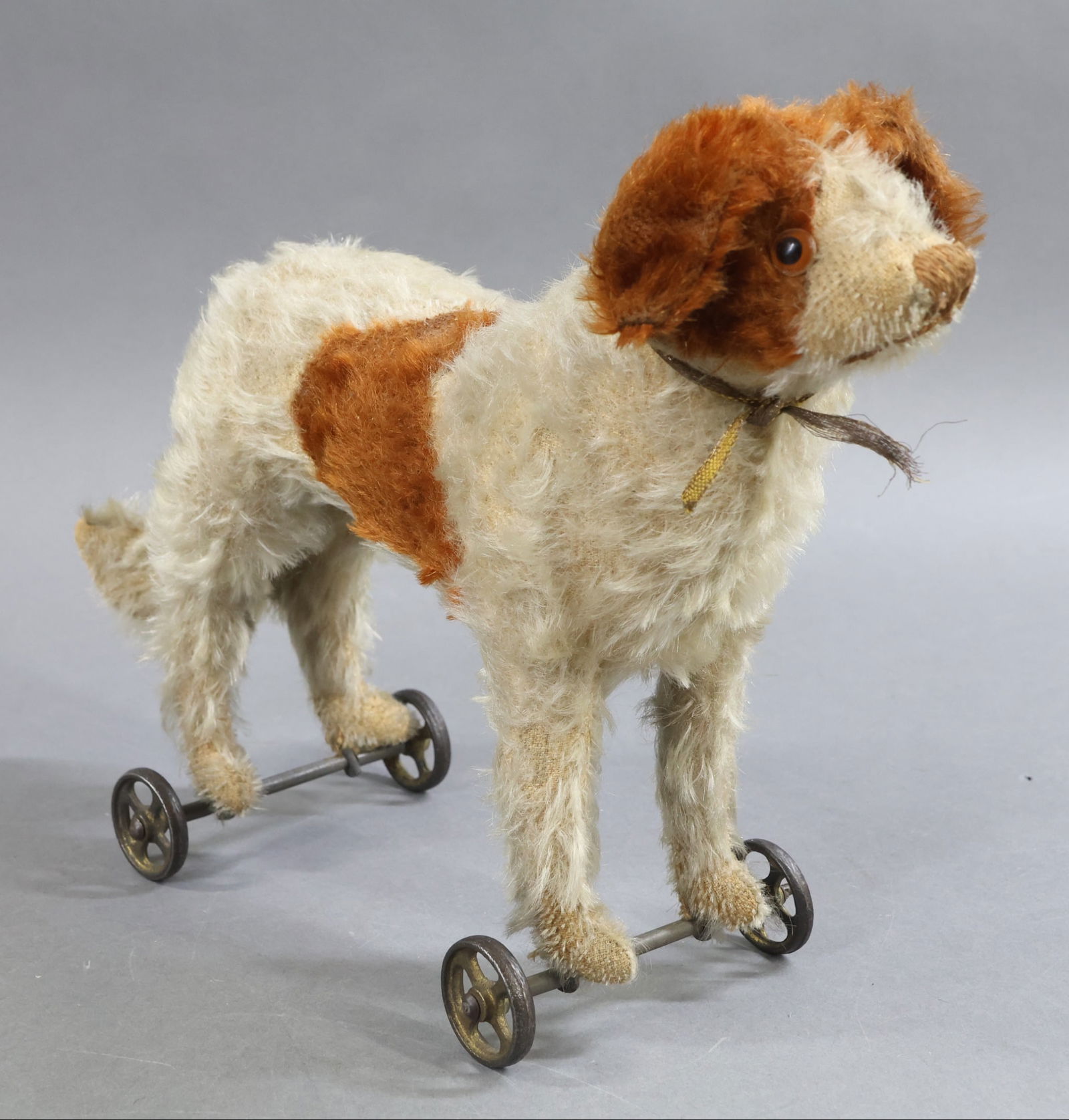 VINTAGE STEIFF.: Tagged mohair 1905-1927 standing "BERNARD", 9" T x 12" L pull toy. White plush with brown spotted markings. Amber glass eyes. Non-working squeaker in stomach. Mounted on metal frame with single spoke