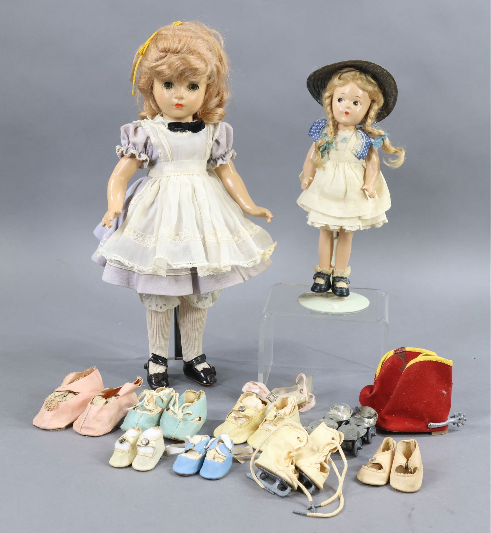 COMPOSITION DOLLS.: LOT. Pair of MADAME ALEXANDER DOLLS and misc. shoes. Both dolls are all original in tagged clothing, oilcloth shoes. They have mohair wigs. Doll 1) 14" "Alice in Wonderland" with honey blonde wig (com