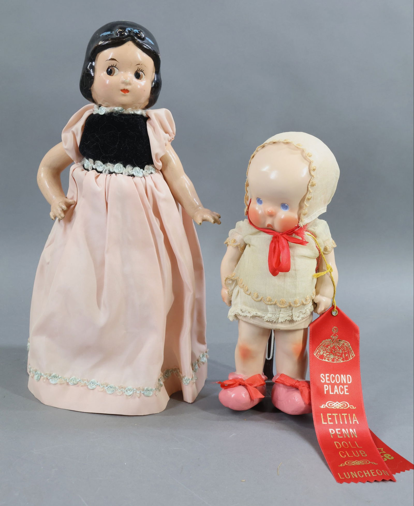COMPOSITION DOLLS.: Pair of dolls. Both dolls have painted features and hair. Clothing on them appears all original. (2) Stands. Doll 1) 11" HORSMAN 1925 "SHE-Bee". Blue eyes, high cheek and knee coloring. Paper label
