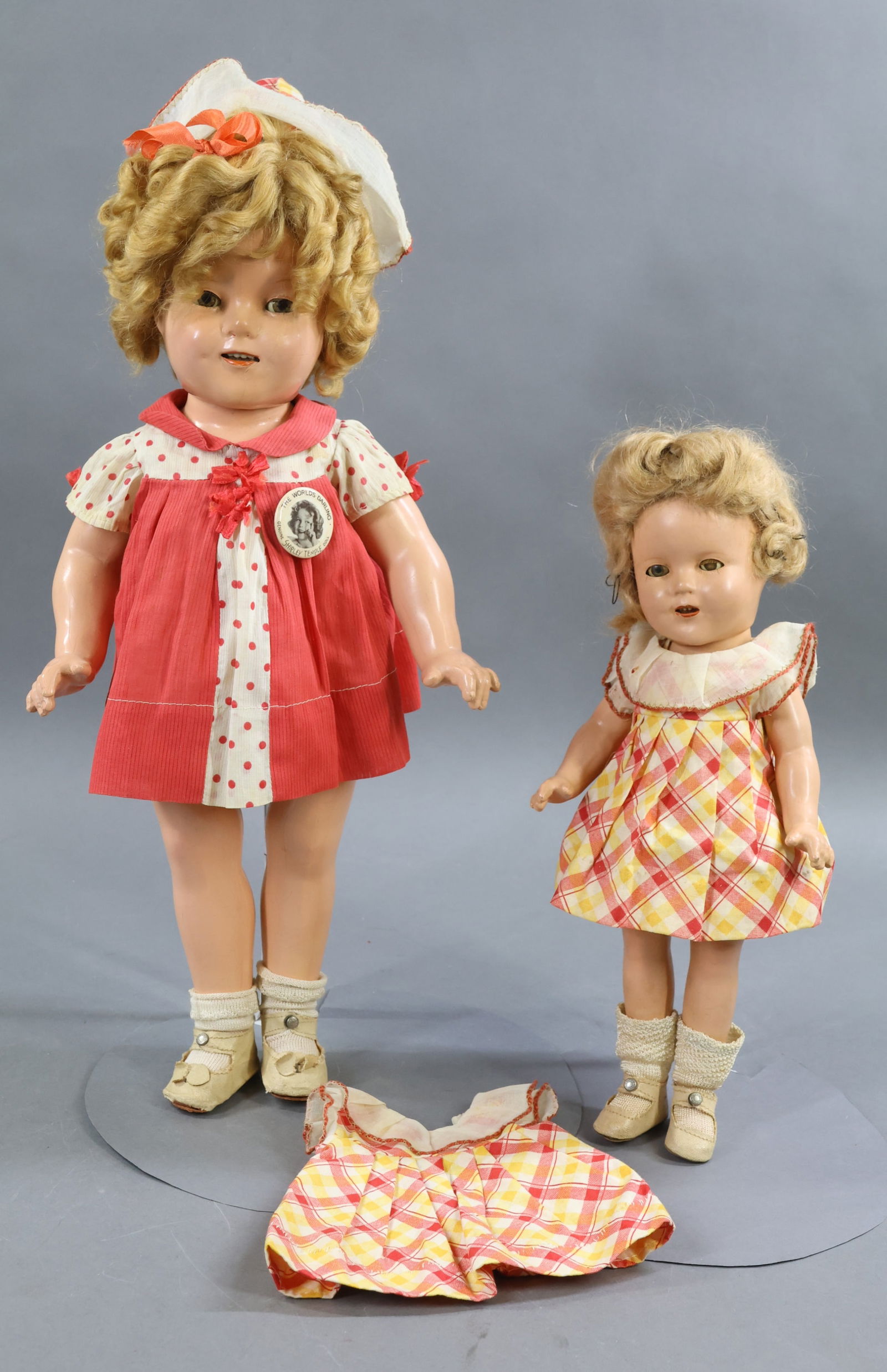 COMPOSITION DOLLS.: Pair of all original IDEAL "Shirley Temple" dolls. Both have their honey blonde mohair wigs, ivory oilcloth center snap shoes, rayon socks. 1 Pc. undergarments. Doll 1) 18" is dressed in original but